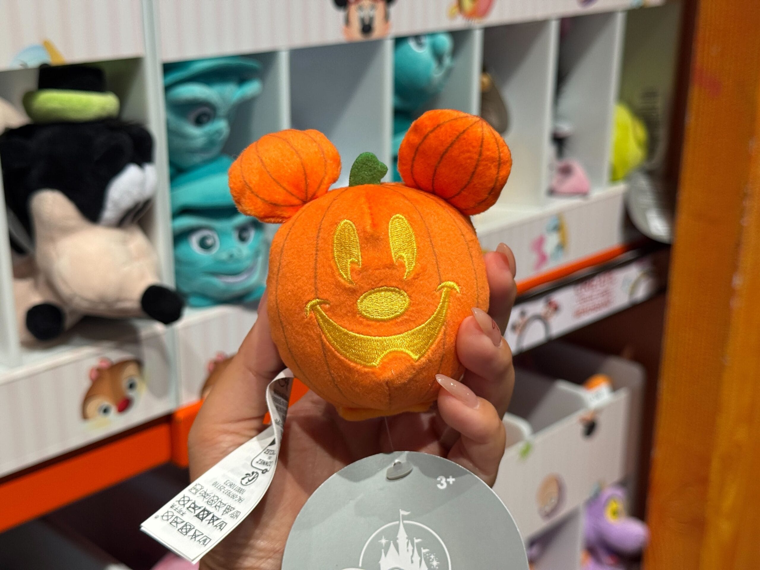 A hand holds a plush pumpkin shaped like Mickey Mouse’s head, part of the Halloween merchandise at Walt Disney World.