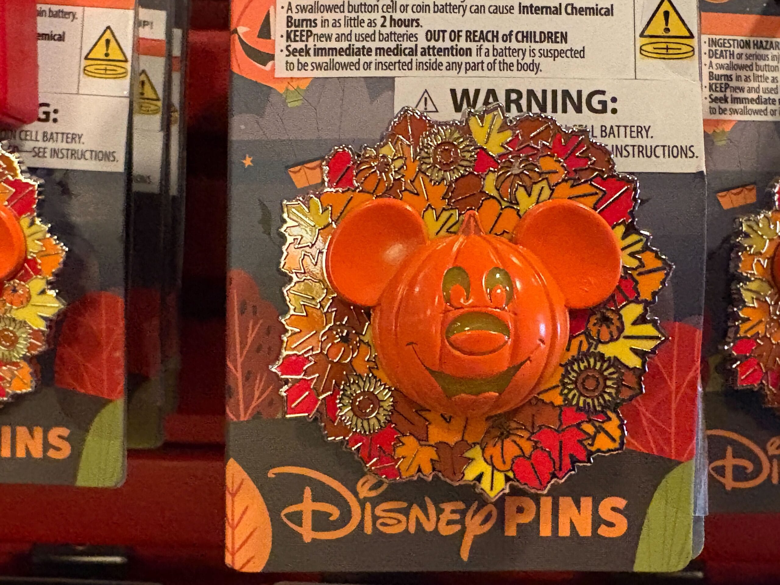 A Walt Disney World pin featuring a pumpkin with Mickey ears, surrounded by autumn leaves from the 2025 Halloween merchandise.