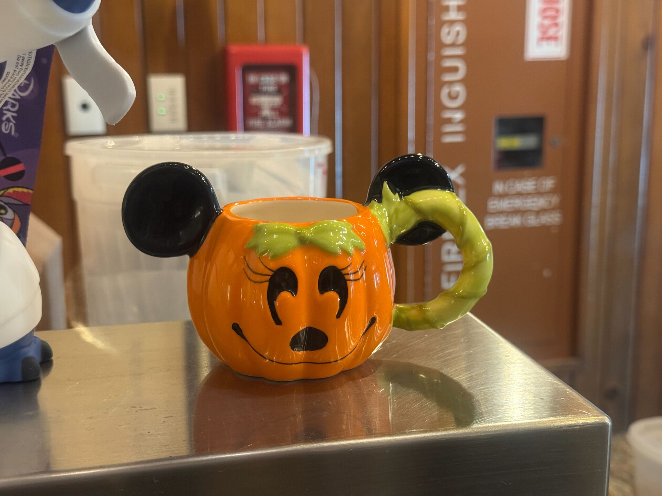 An exclusive Disneyland Halloween Minnie Demitasse mug with black mouse ears, a green bow, and a smiling pumpkin face.