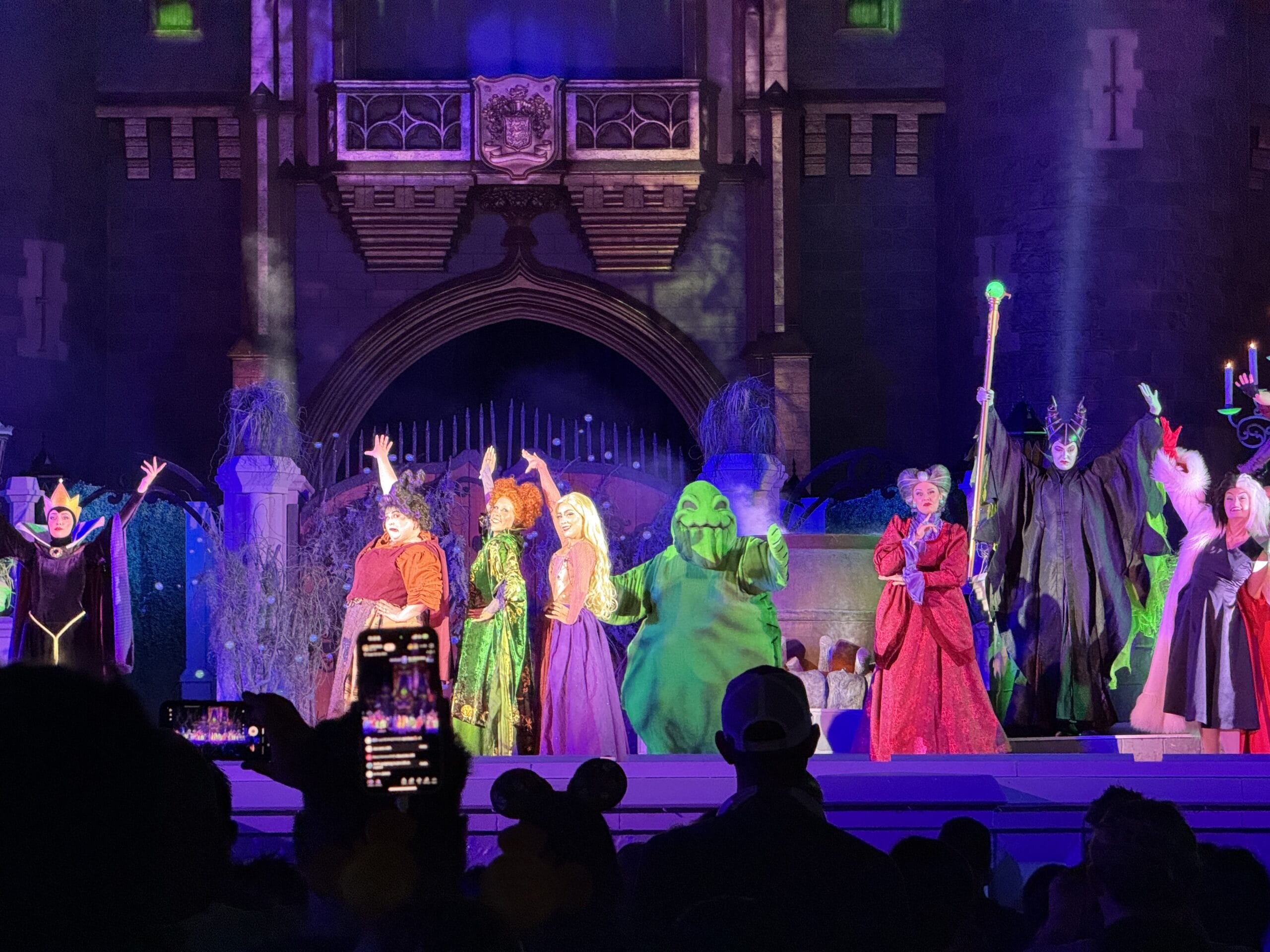 Costumed Disney villains perform on stage at night during Oogie Boogie Bash, thrilling the watching audience.