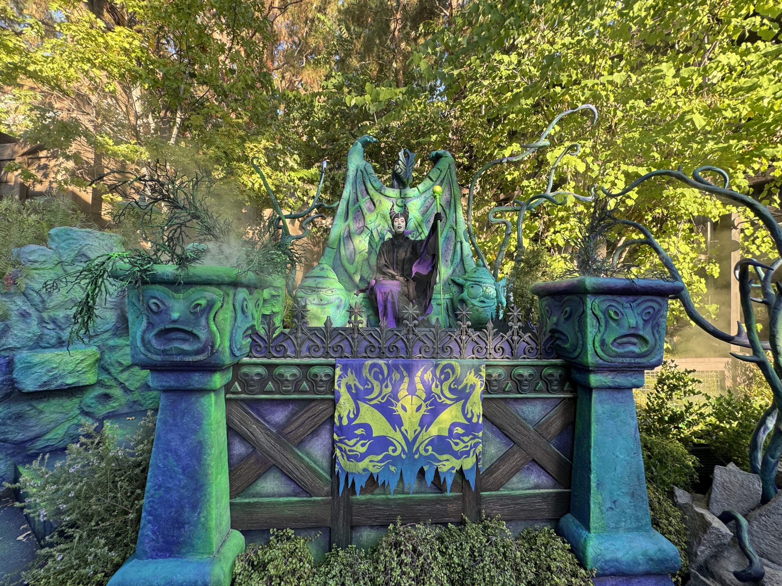 A person in a Maleficent costume stands on a fantasy float at Mickey's Not So Scary Party, surrounded by green and purple.