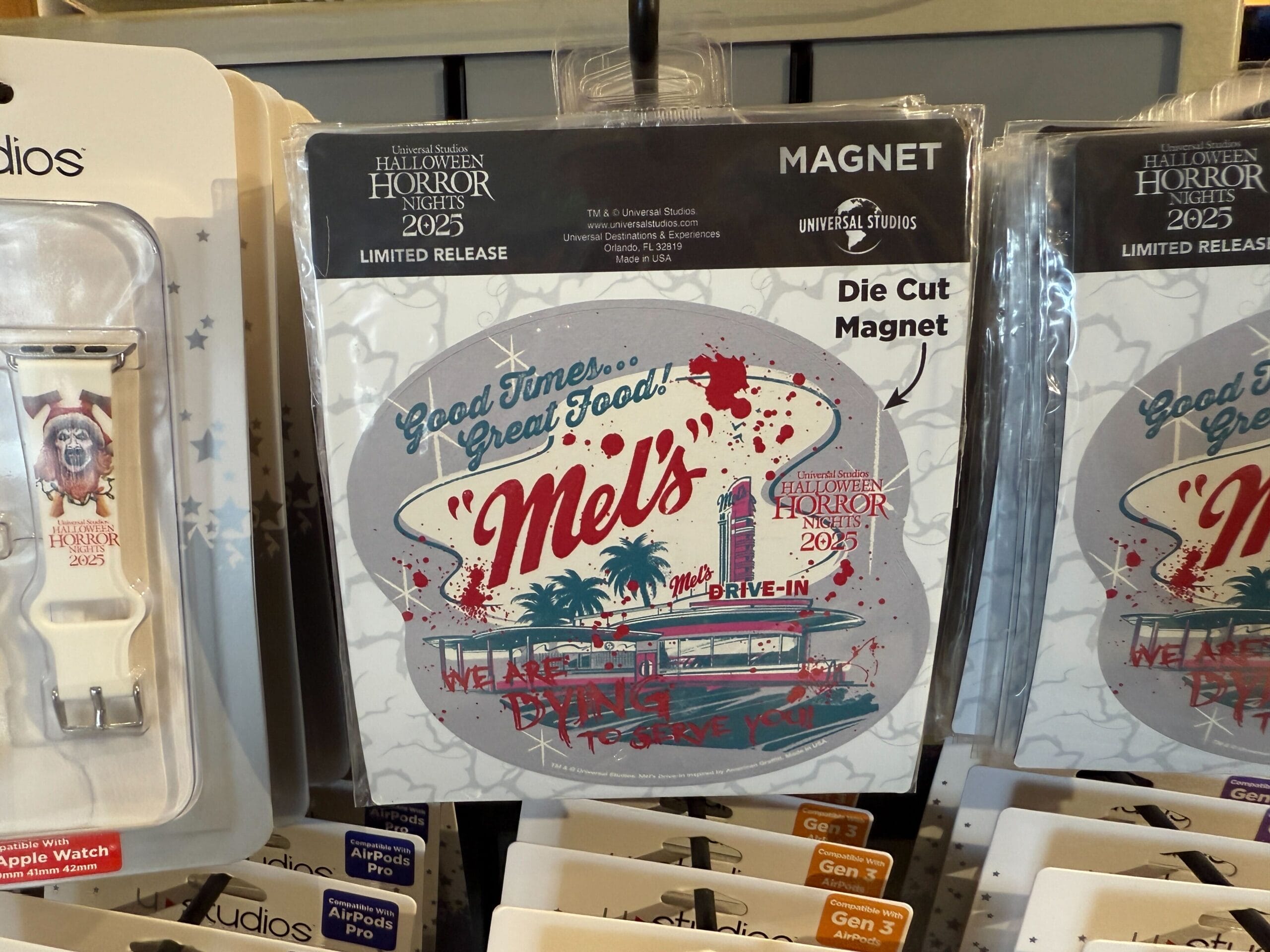 A round Mel's Drive-In magnet featuring HHN Merch 2025 hangs on a store display rack at Universal Orlando Resort.