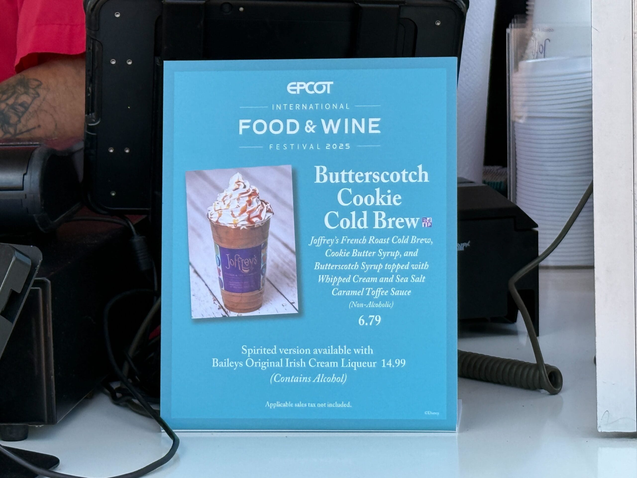 A blue sign at the Food & Wine Festival advertises Butterscotch Cookie Cold Brew with price and drink details.
