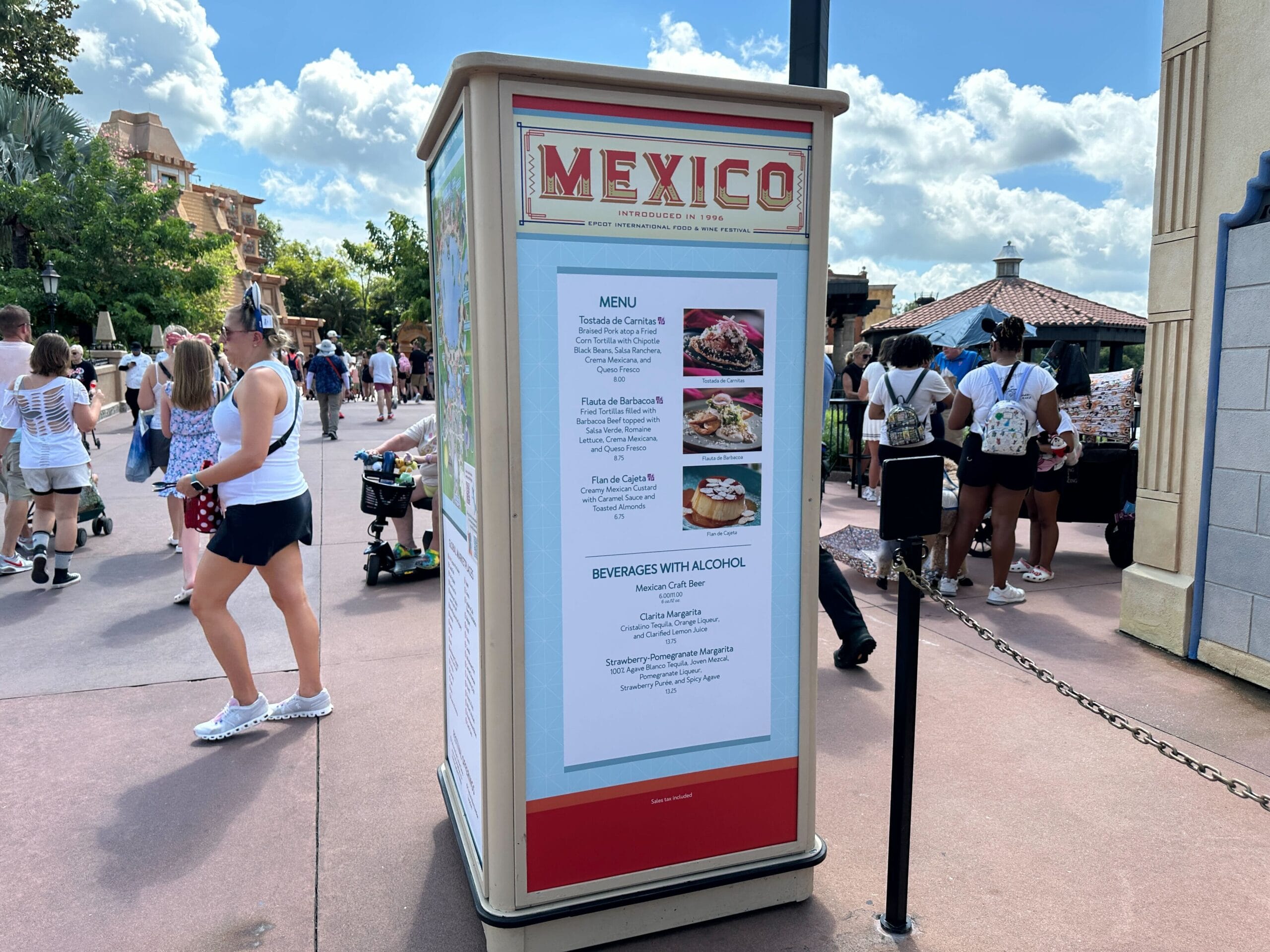 Outdoor Food & Wine menu kiosk for the Mexico Pavilion at Epcot, listing options with people walking nearby.