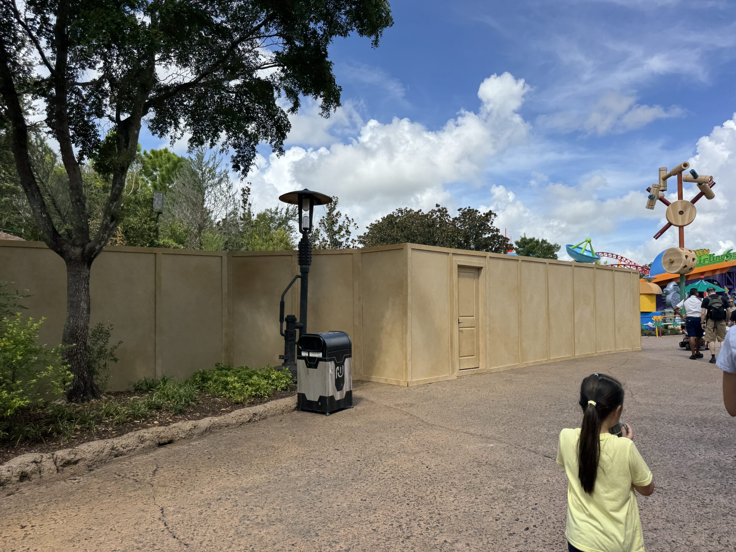 Construction walls and equipment border a walkway at Hollywood Studios in this 2025 Photo Report; people walk nearby.