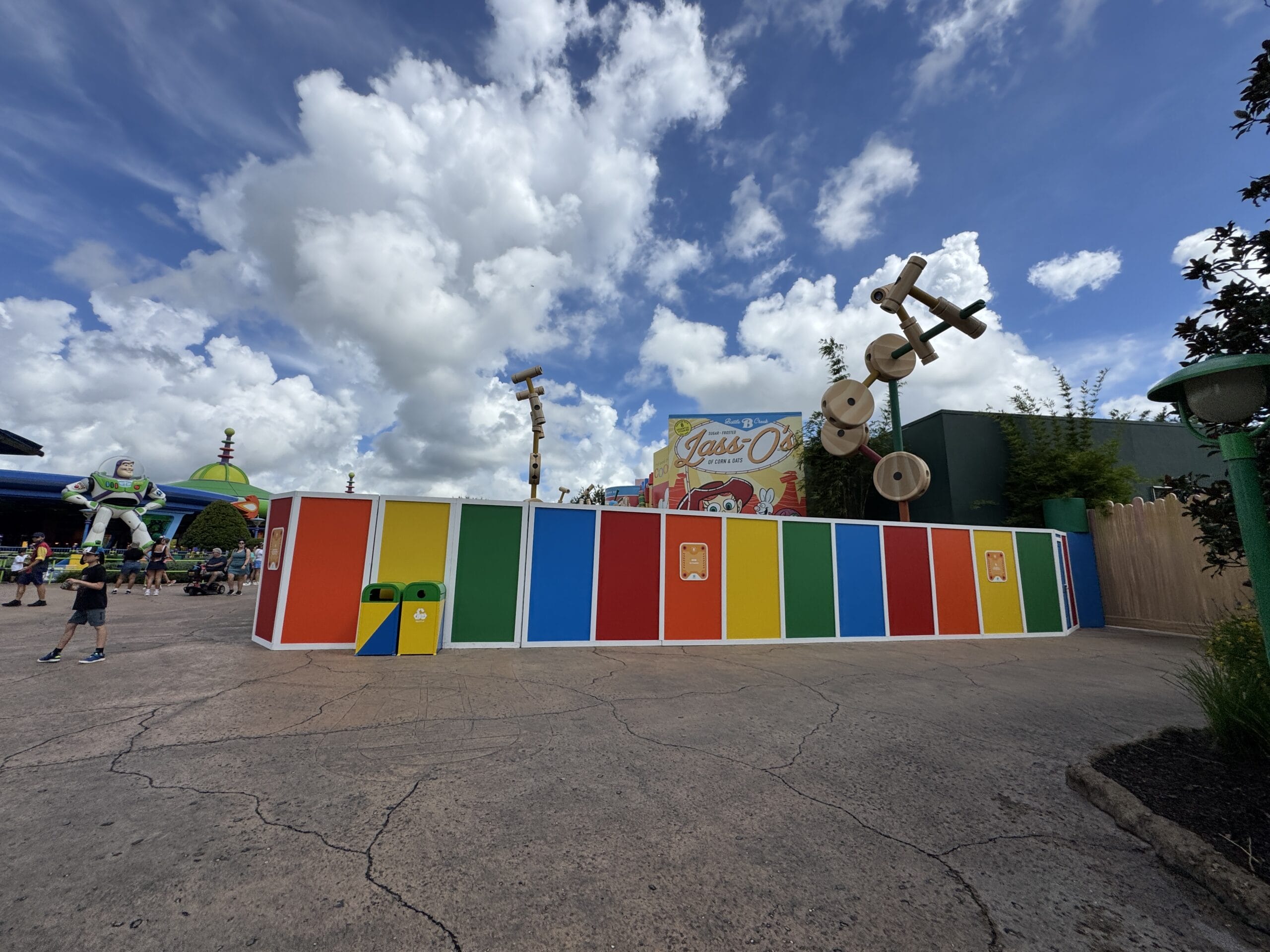 Colorful construction wall in Toy Story Land at Hollywood Studios, with Buzz Lightyear and toy decorations under a cloudy sky.