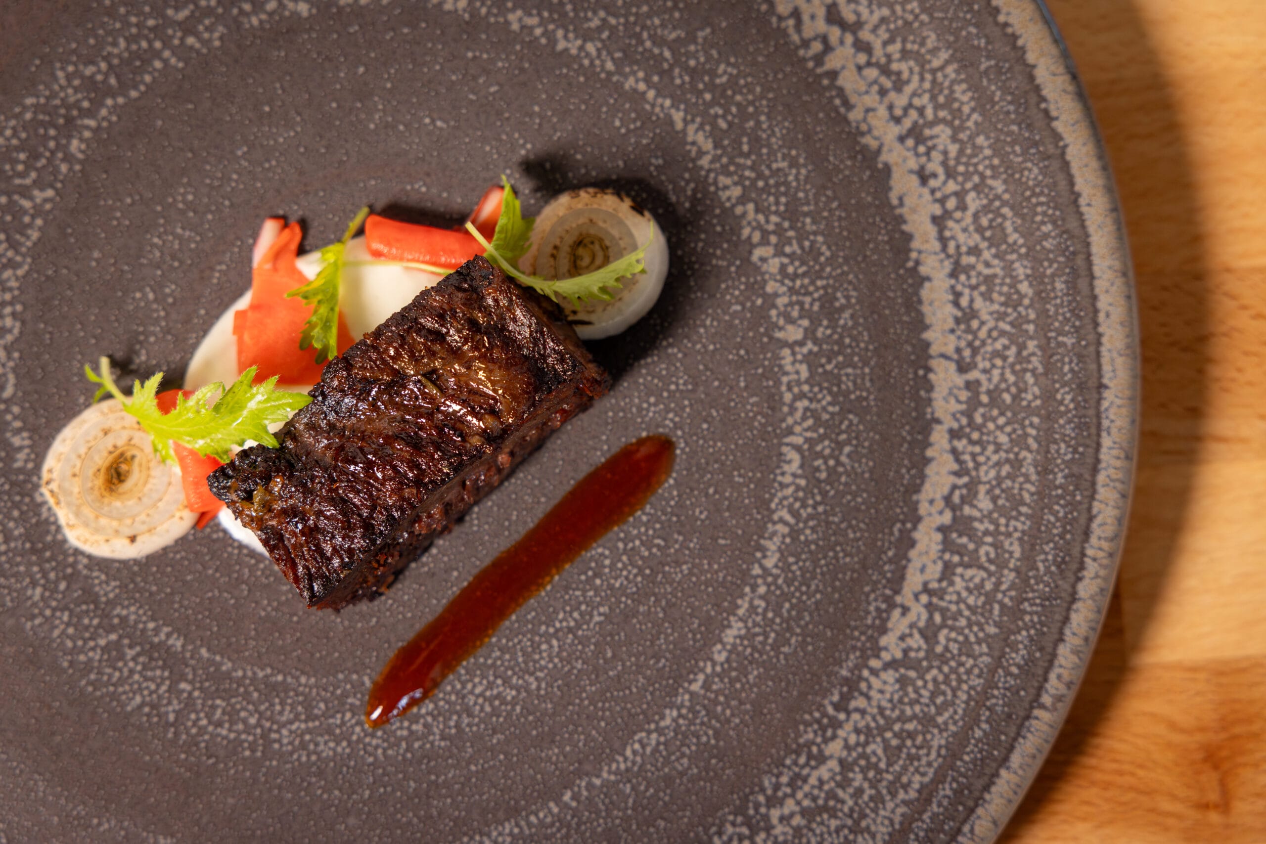 A small, grilled meat portion with sauce and vegetables, artfully plated for the Swan and Dolphin Food & Wine Classic.