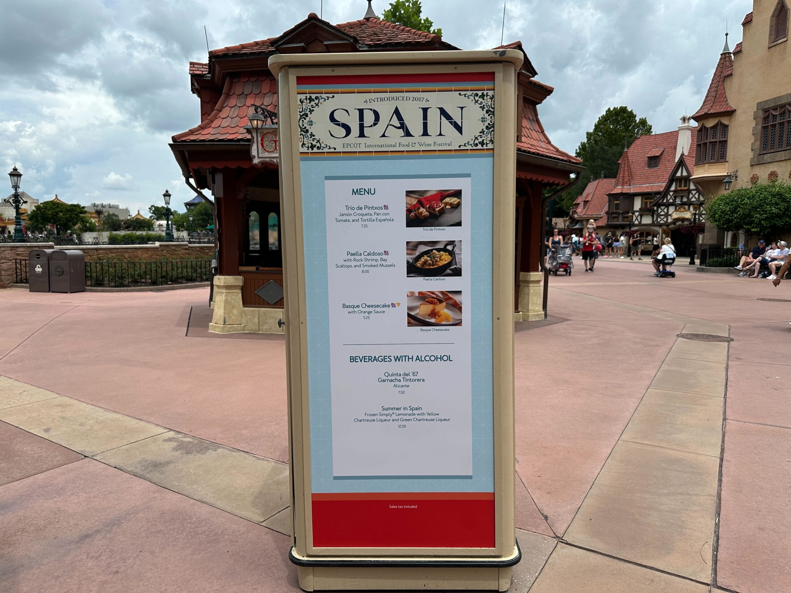 Outdoor Food & Wine menu board for Spain at a theme park, set against European-style buildings in the background.