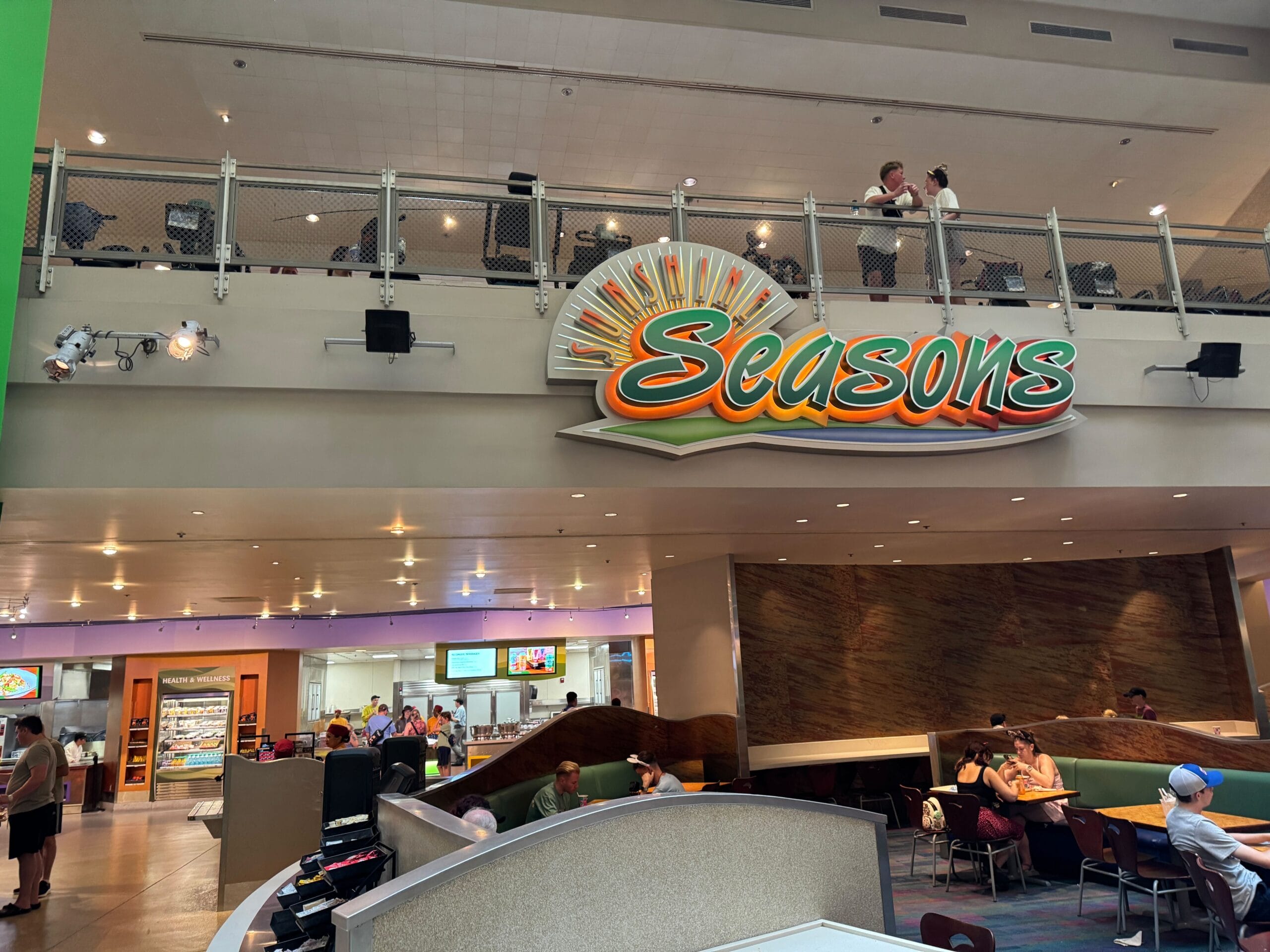 The entrance to Sunshine Seasons restaurant, glowing with a bright neon sign, welcomes Food & Wine lovers dining inside.