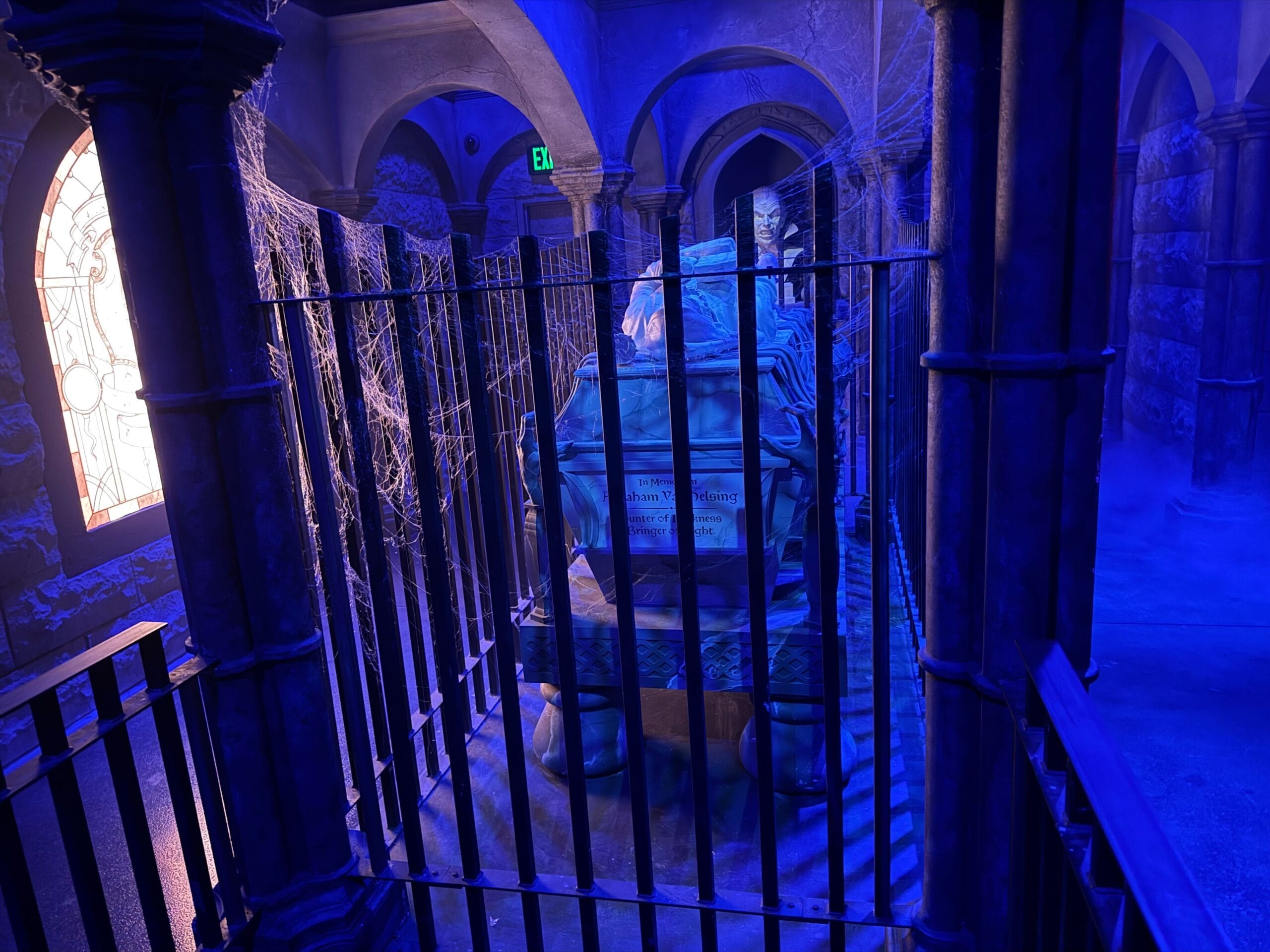 A dimly lit, blue-hued tomb with cobwebs evokes the eerie spirit of Universal Monsters in a gothic setting.