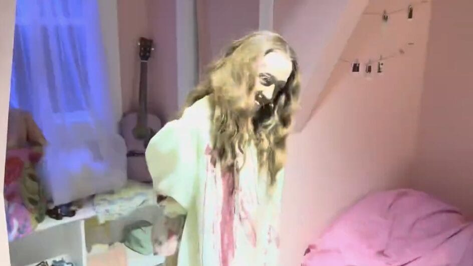 A person in a white robe with long hair stands in a pink bedroom, evoking The Exorcist: Believer’s haunting style.