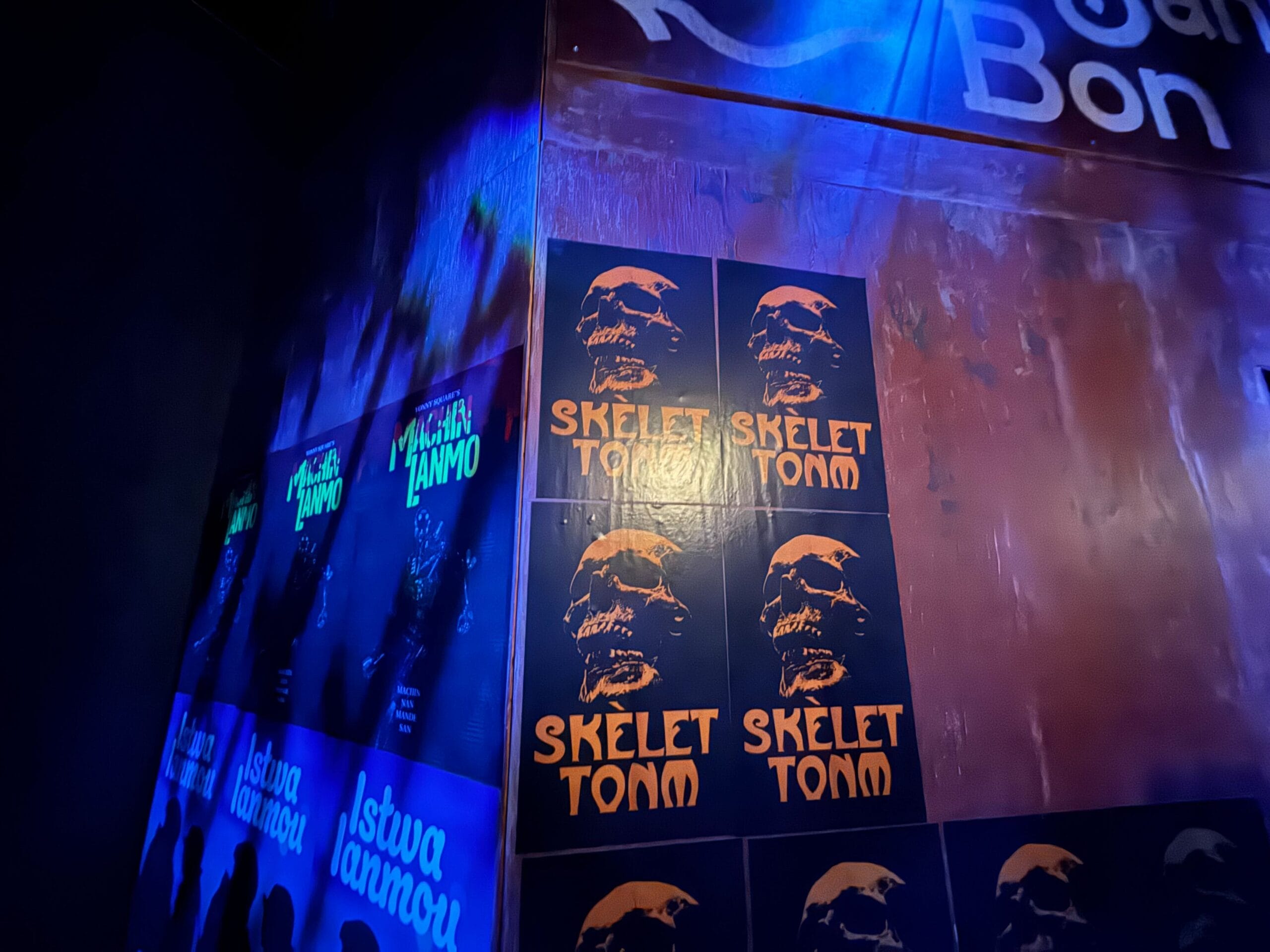 Posters with an orange skull and "SKELET TONM" text appear on a dark, blue-lit Universal Horror Unleashed wall.
