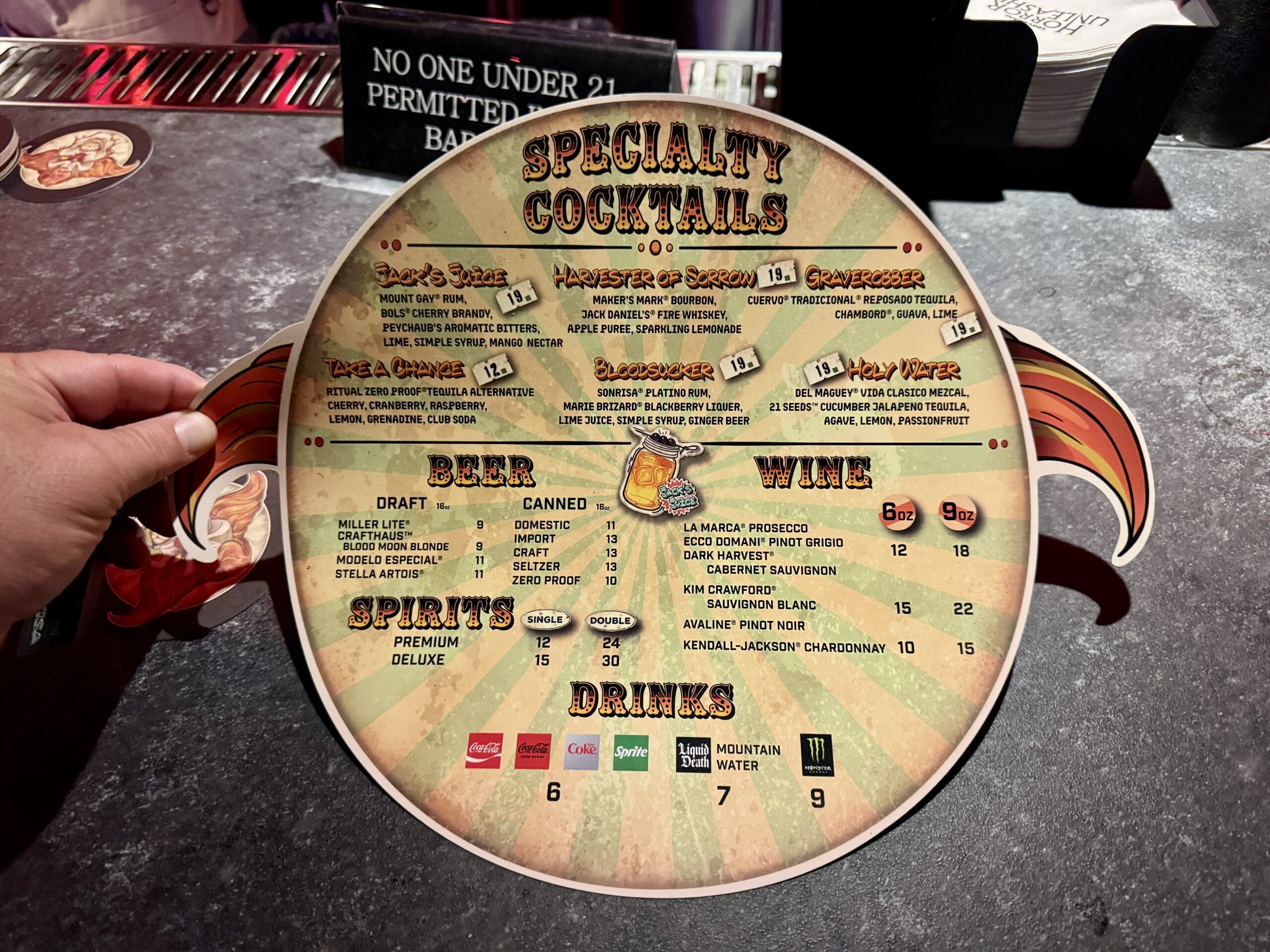 A round bar menu for Jack's Alley Bar in Las Vegas displays specialty drinks; a hand holds it.