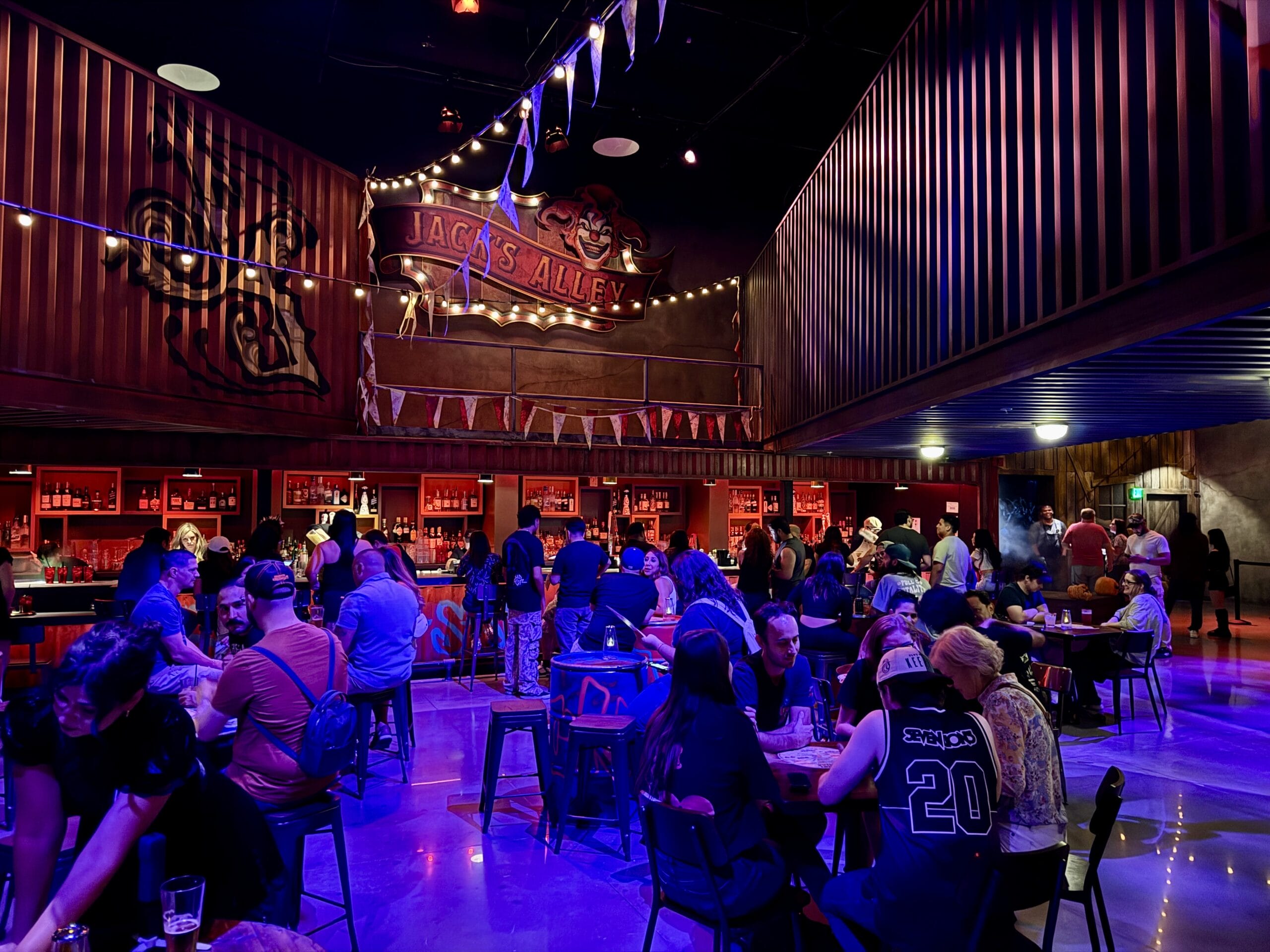 A lively Las Vegas bar with people socializing, string lights overhead, and a "Jack's Alley" sign on the back wall.