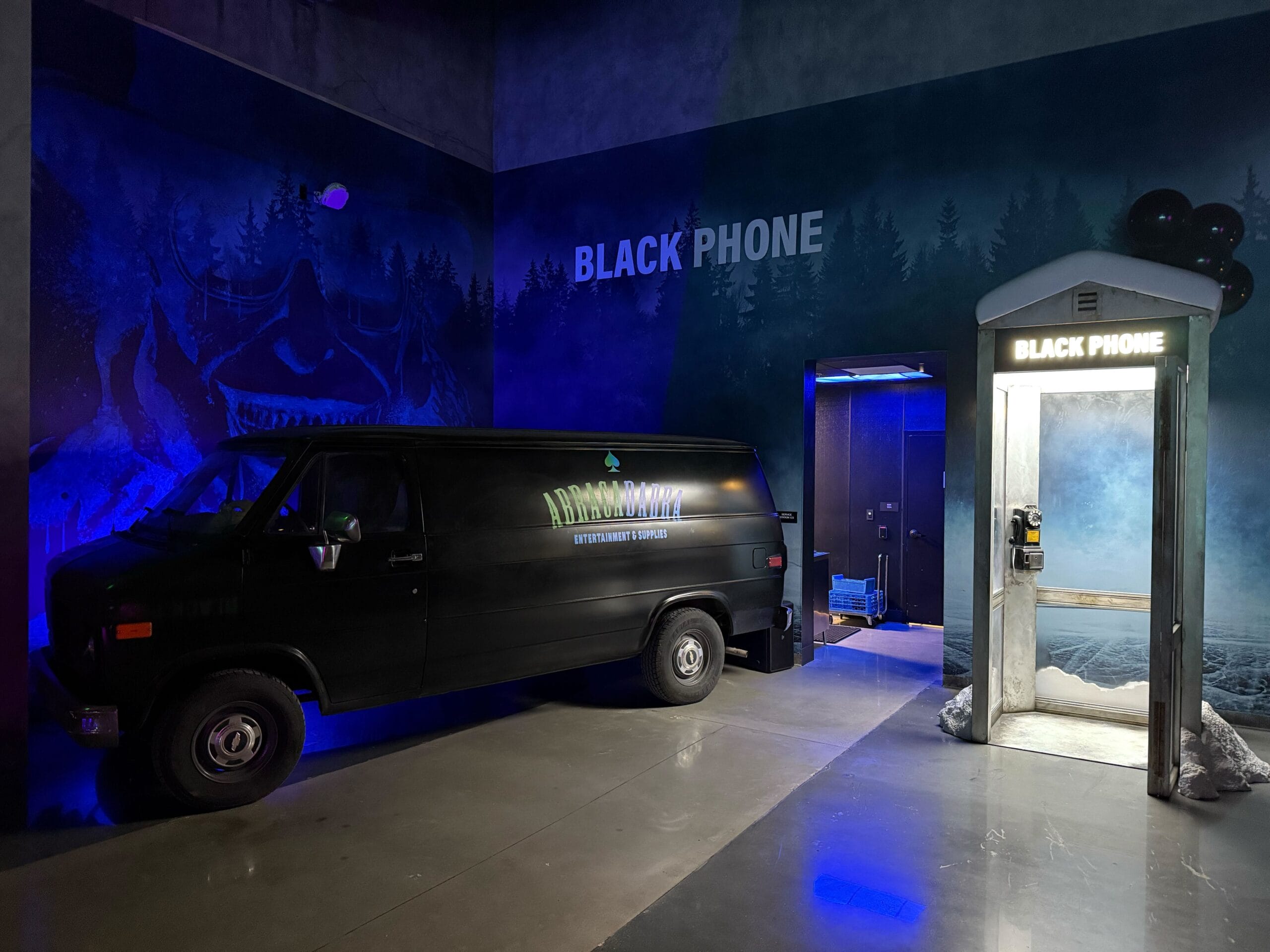 A black van and old "BLACK PHONE" booth in a dimly lit Las Vegas room, inspired by Universal Horror Unleashed.
