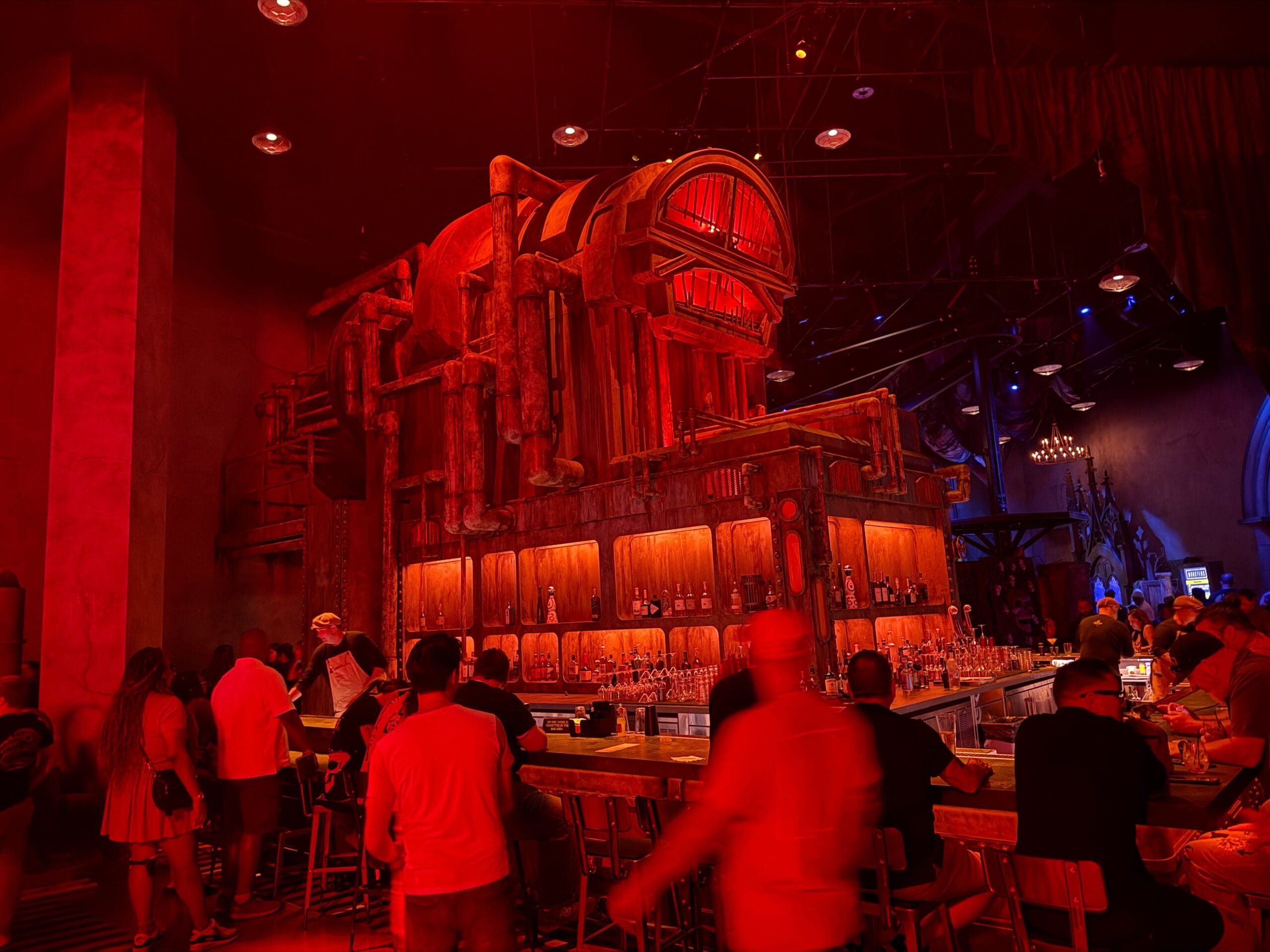 Bar scene at The Boiler, Las Vegas, with people mingling under red light and an industrial Universal Horror Unleashed vibe.
