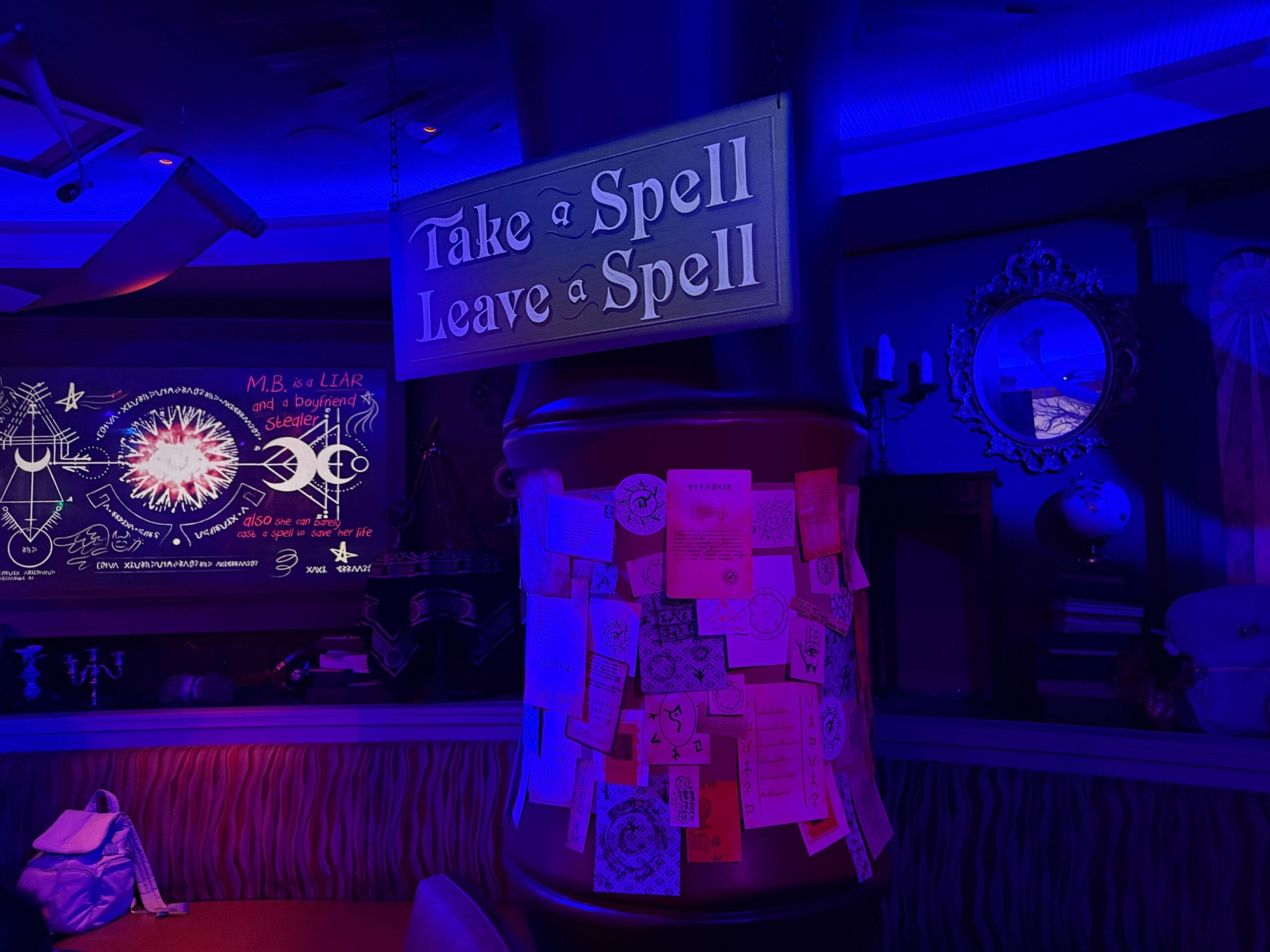 A sign reads “Take a Spell Leave a Spell” above a pillar of notes in the mystical Dead Coconut Club.