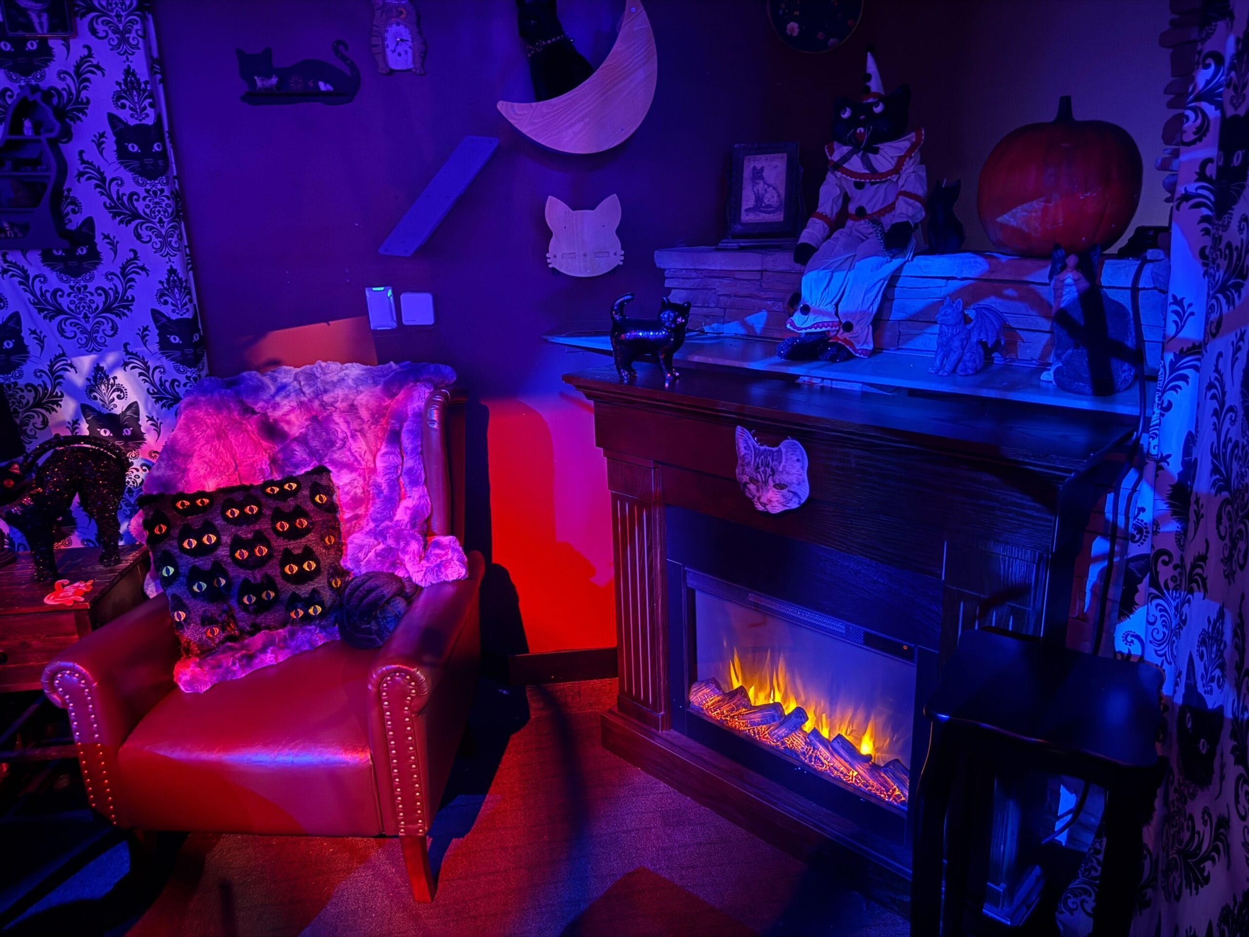 A cozy room with cat decor, a faux fireplace, and purple-blue lights—perfect for a Sorority Witches full tour.