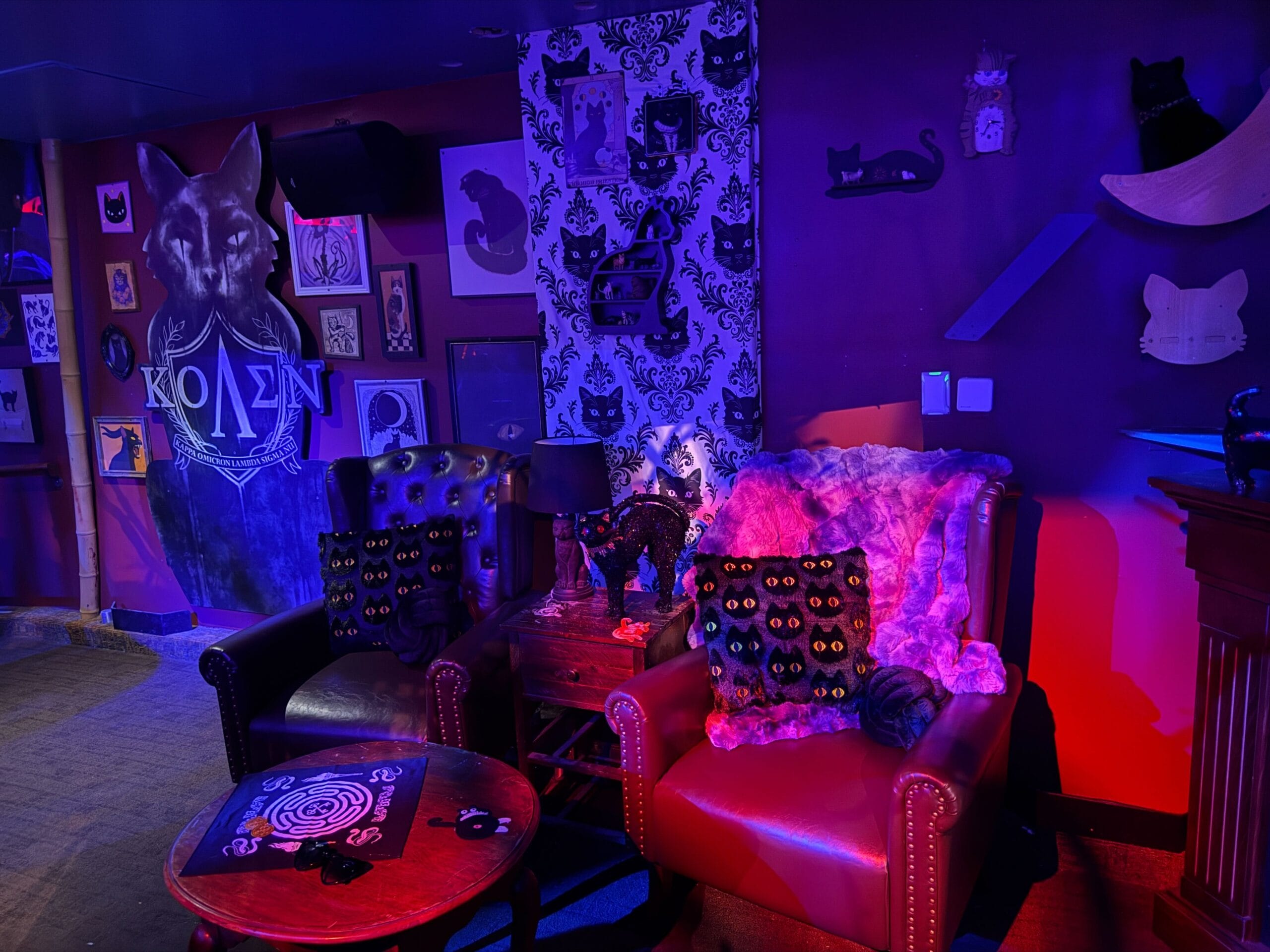 A cozy, dimly lit lounge with cat-themed decor, plush chairs, and a hint of Dead Coconut Club ambiance.