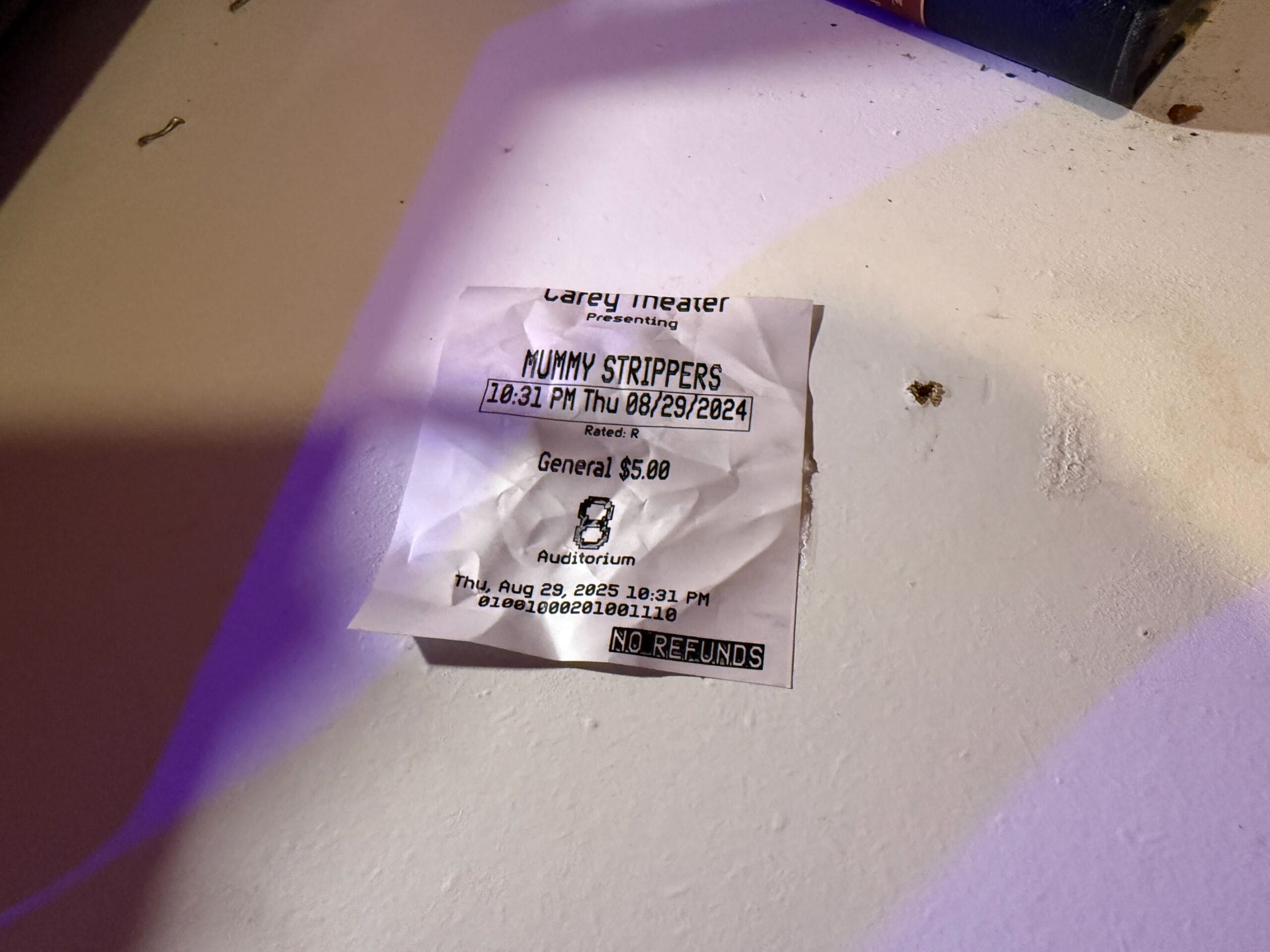 A crumpled "Mummy Strippers" tour ticket at Carey Theater, August 29, 2024, on a white surface.
