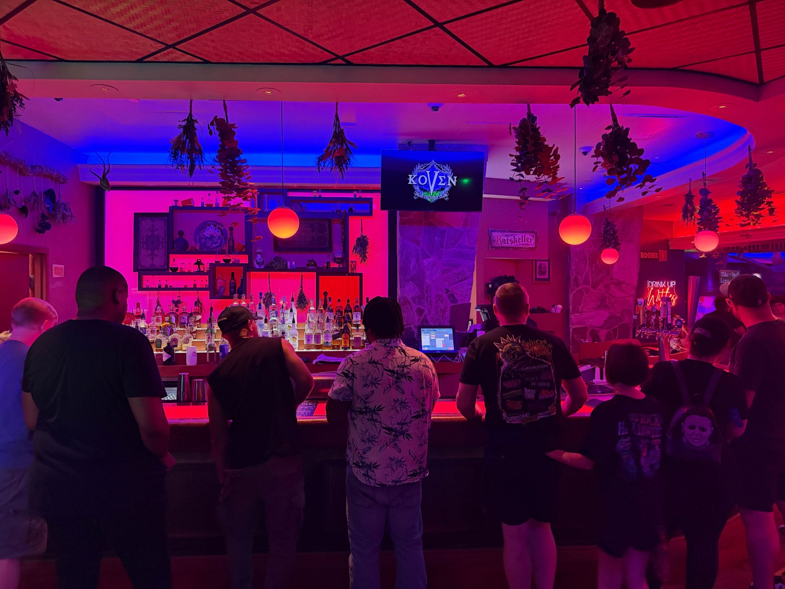 People gather at the Dead Coconut Club, a neon-lit bar with red and purple lights, on the Sorority Witches Tour.