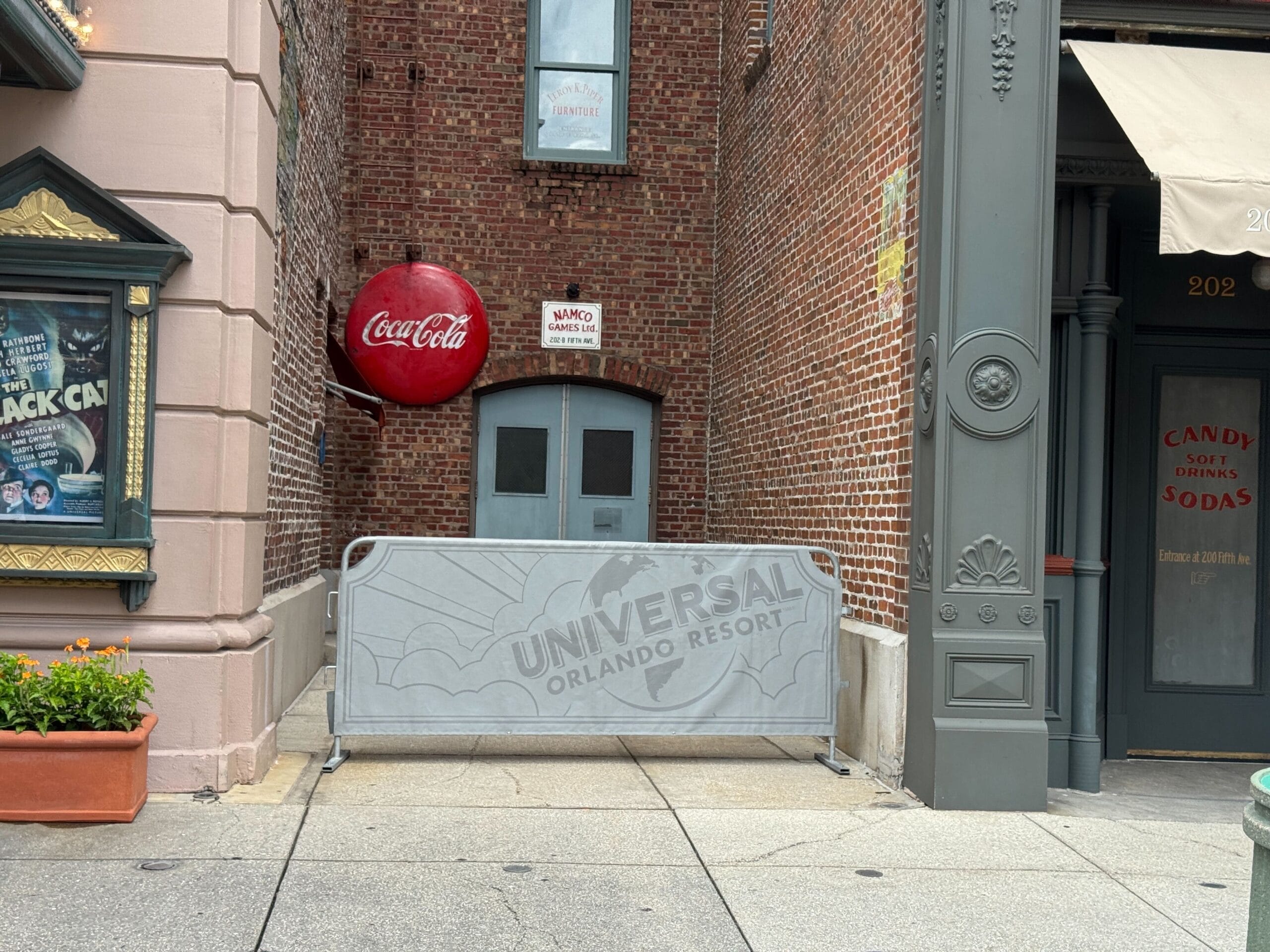 A Universal Orlando Resort barricade blocks a brick alley near the Tribute Store and a "No Thru Traffic" notice.