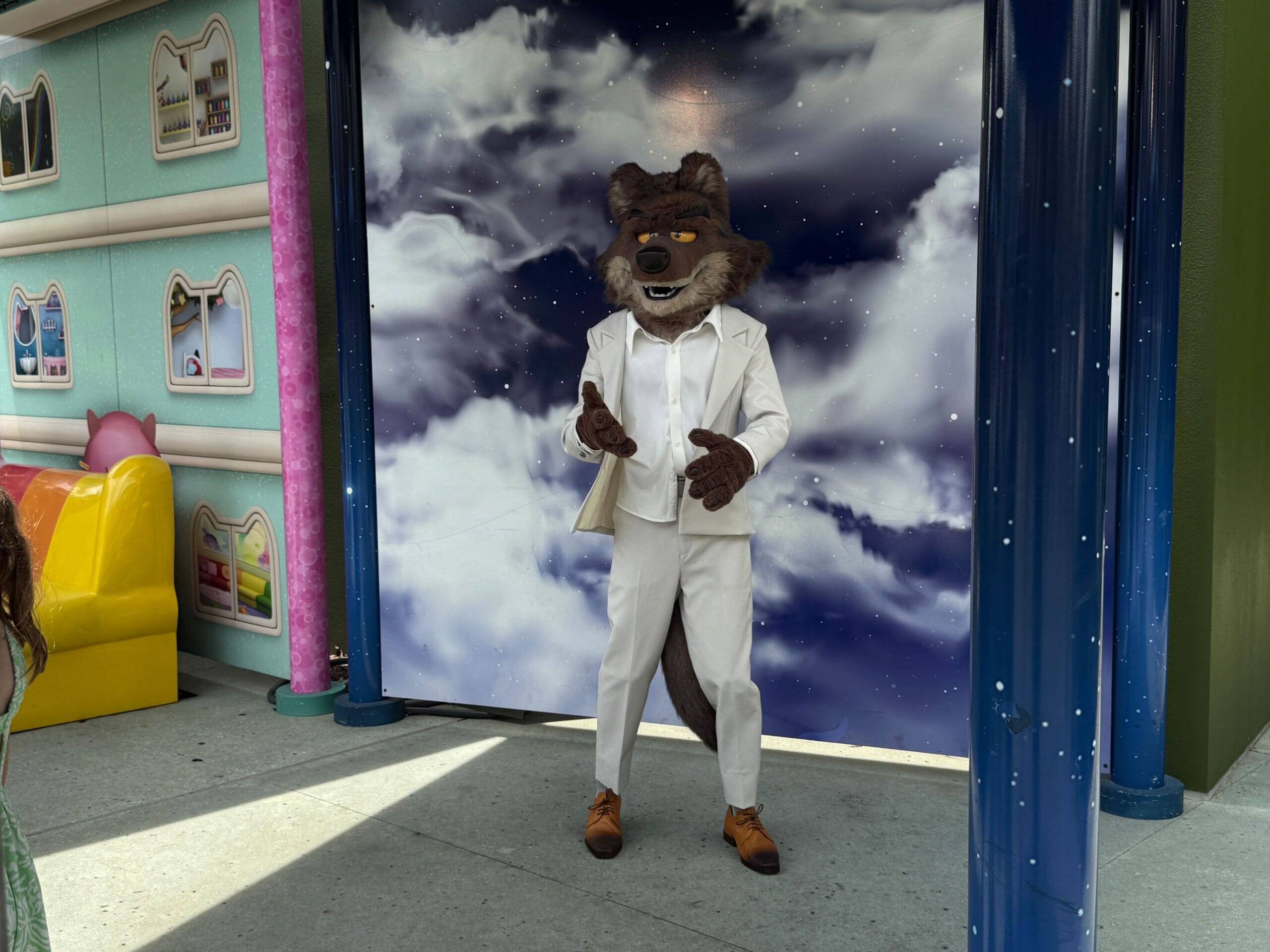 A person dressed as Mr. Wolf in a white suit poses at an outdoor venue, echoing scenes from Bad Guys Films.