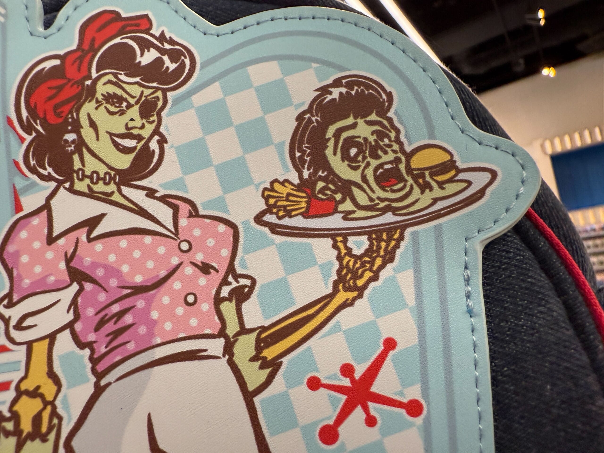 Cartoon zombie waitress at Mel's Die-In holding a tray with a severed head, burger, and fries on blue checks.