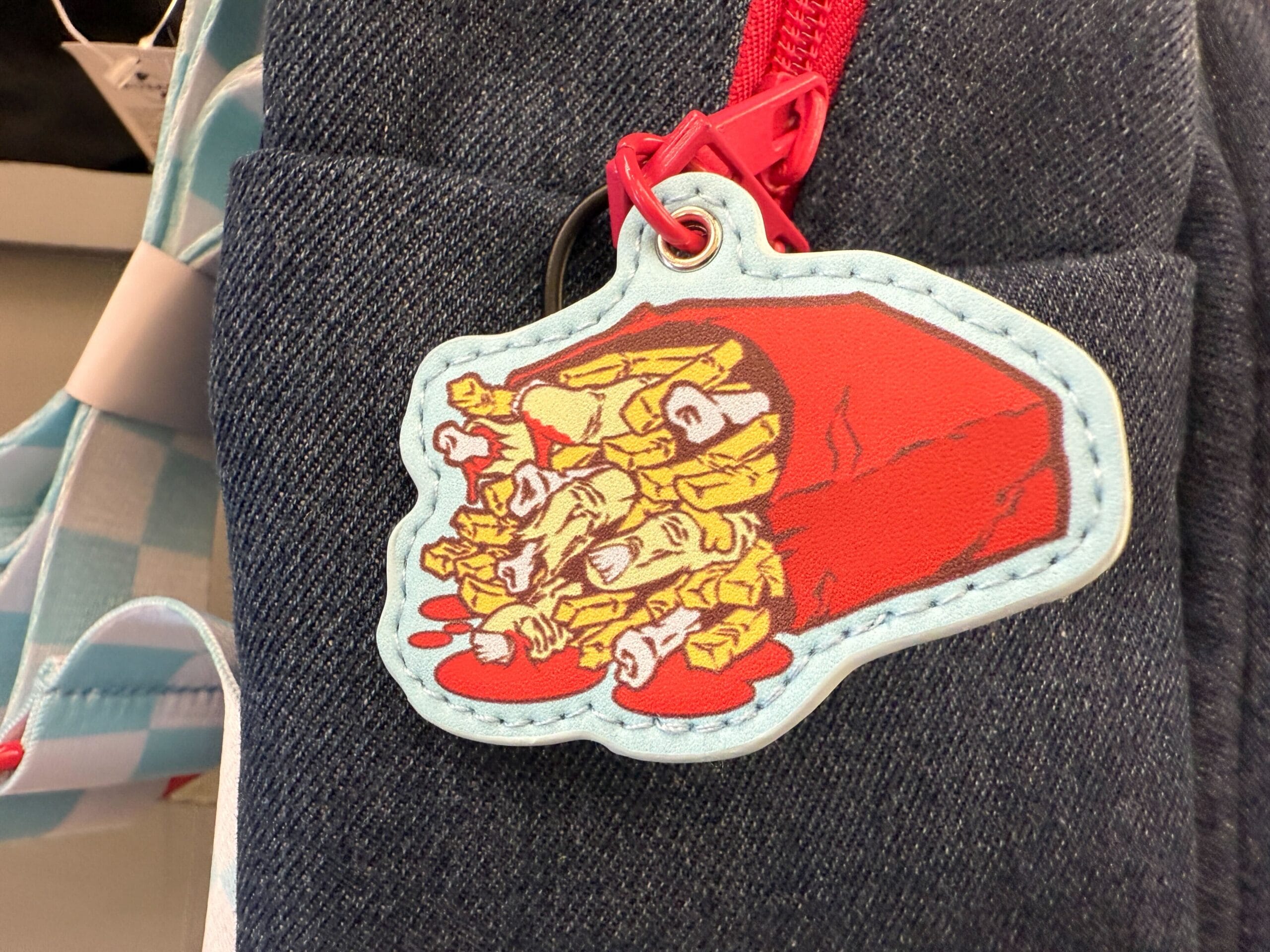 A denim bag from Mel's Die-In merch, featuring fries in a red coffin with ketchup spilling out like zombie blood.
