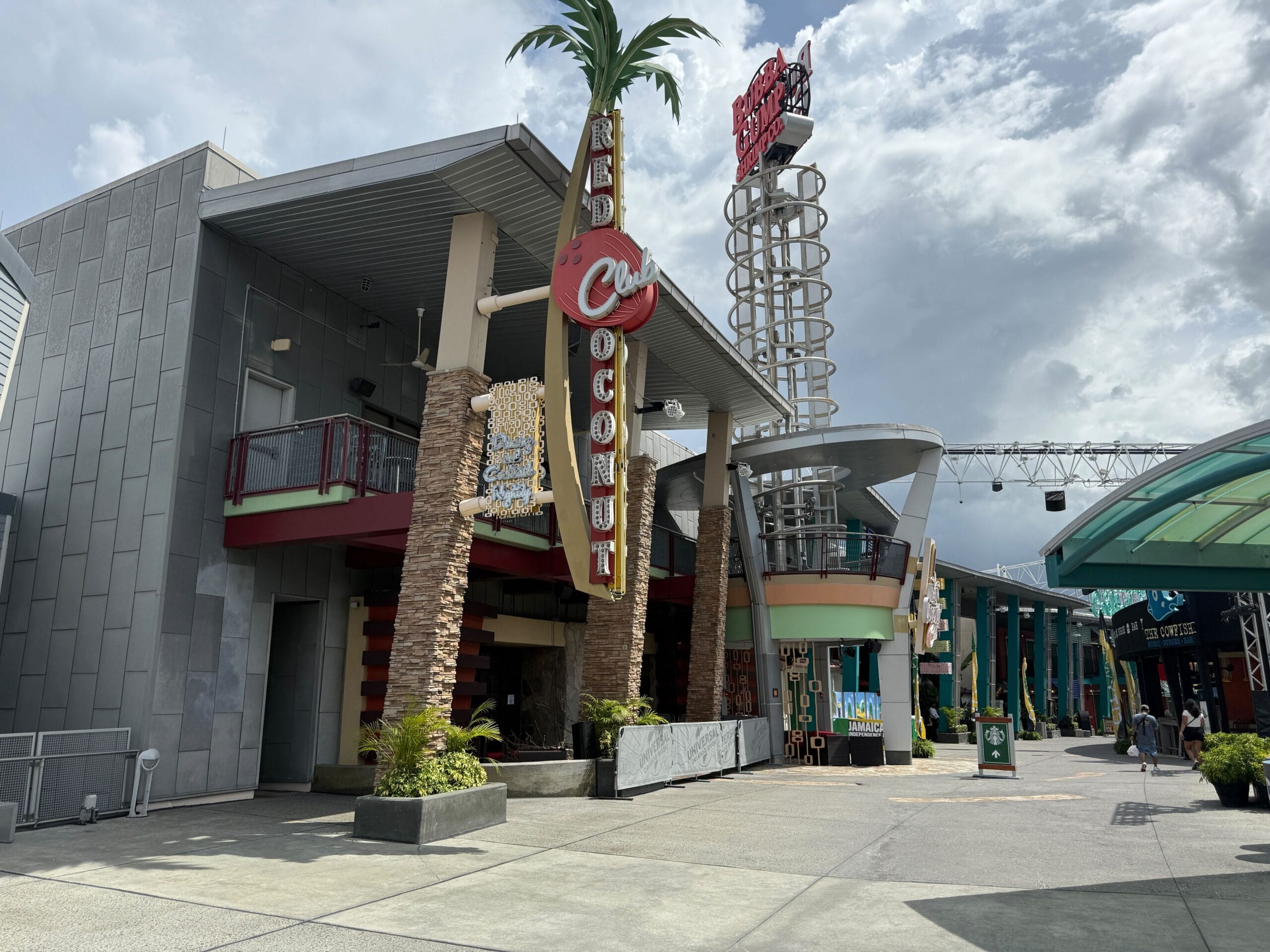 Outdoor view of the Red Coconut Club with palm decor and a Firefly Fun House sign for Halloween Horror Nights 34.
