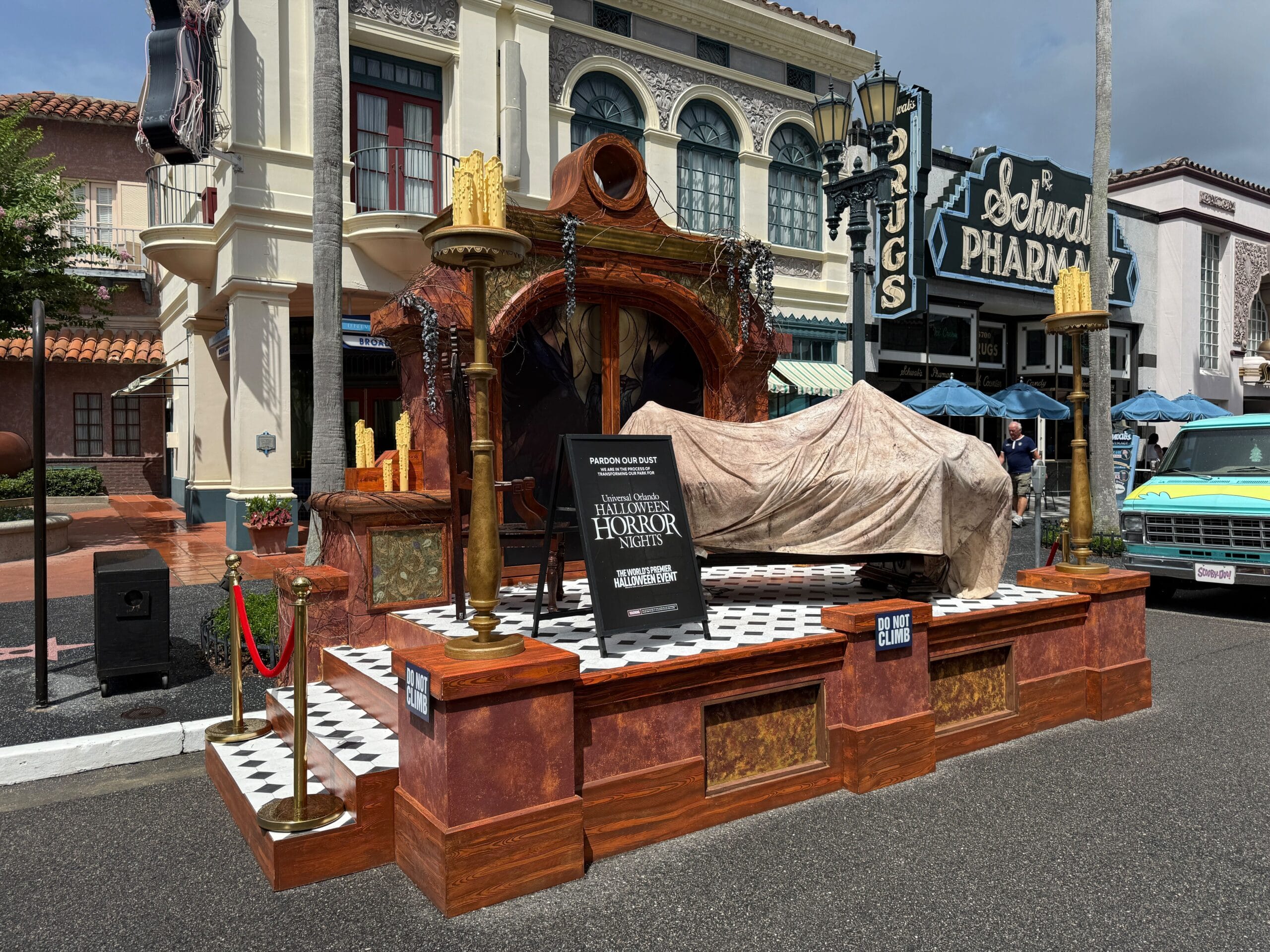 A spooky stage with a covered figure, gothic props, and a Clown Cafe sign for Halloween Horror Nights 34.