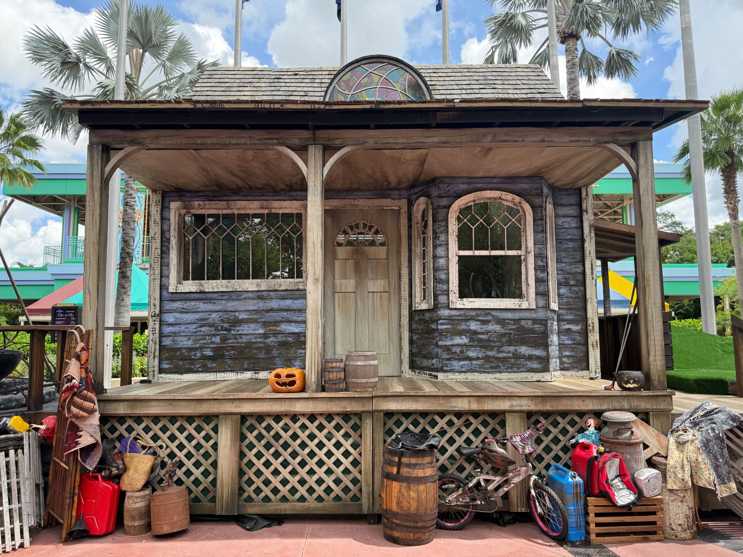 A weathered porch with carved pumpkins, barrels, and a Firefly Fun House Sign for Halloween Horror Nights 34.
