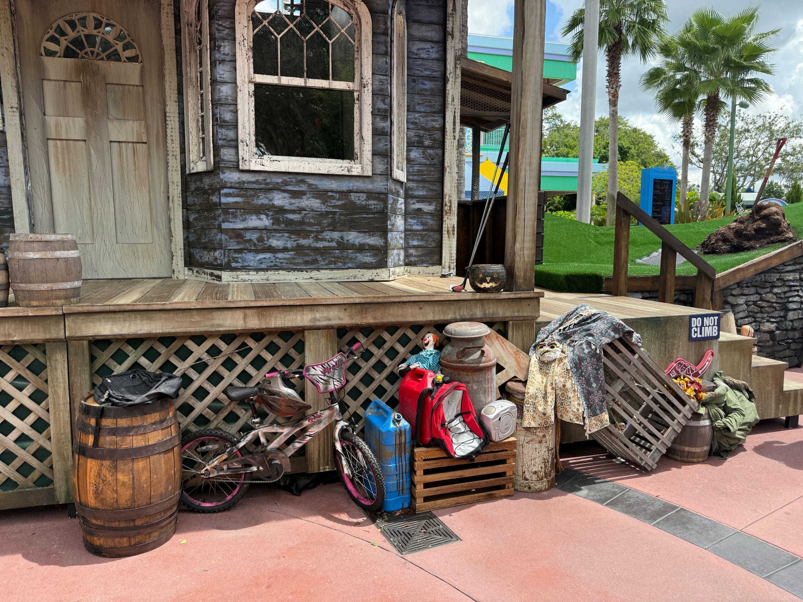 Assorted old items, a bike, and barrels sit by a porch with a Firefly Fun House sign for Halloween Horror Nights 34.