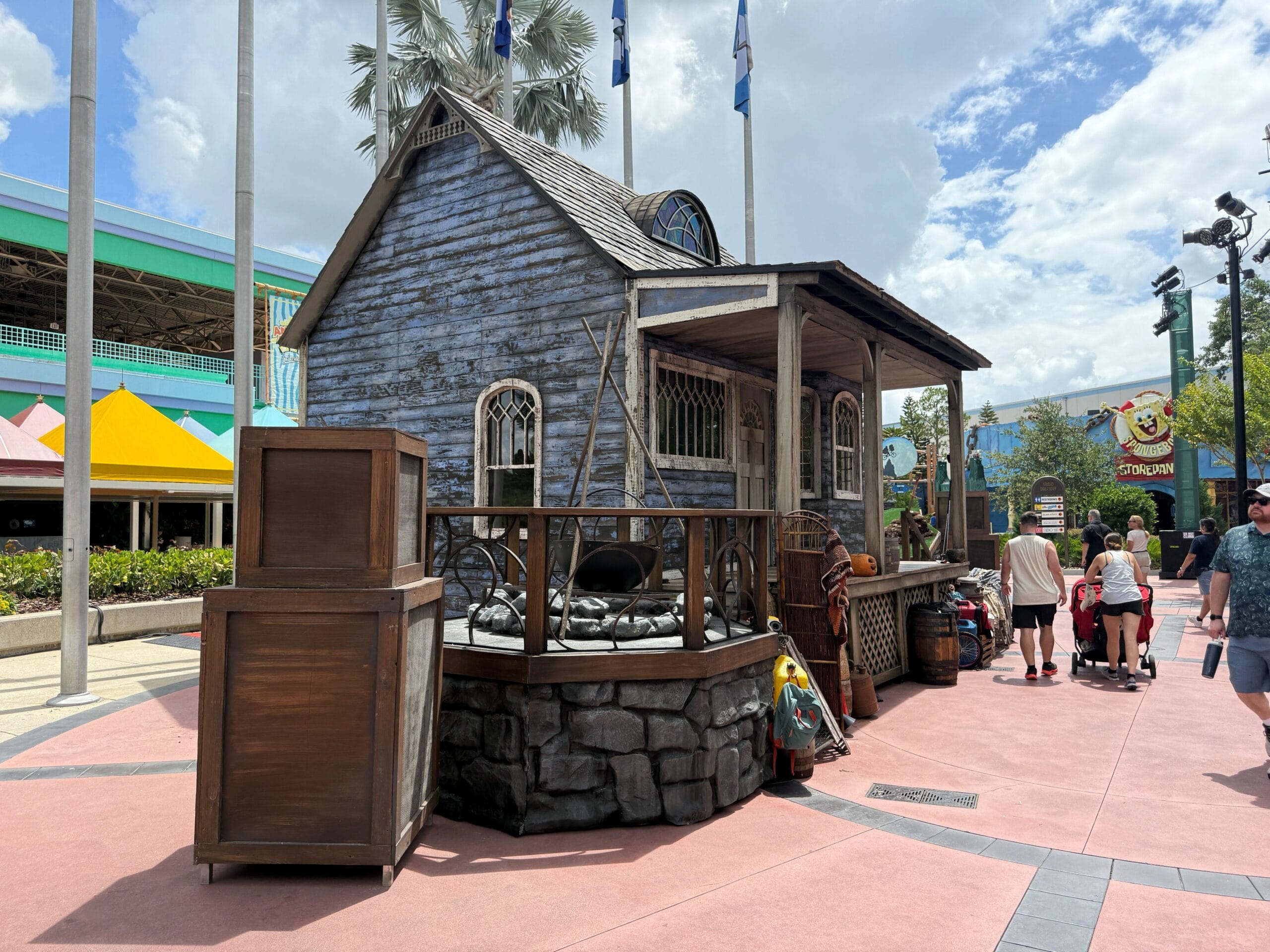 A weathered wooden shack with barrels sits on a theme park path near Terrifer's Clown Cafe at Halloween Horror Nights 34.