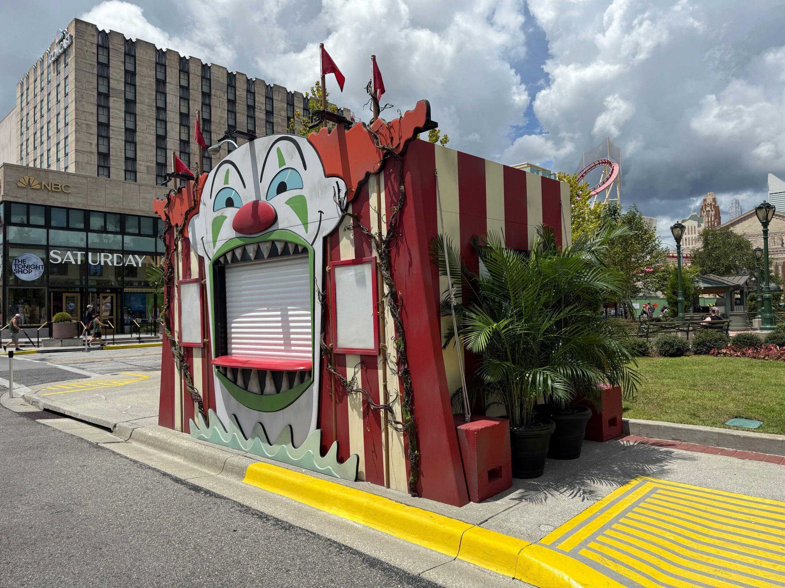 Red and white Clown Cafe booth with a clown face, outdoors near palms—perfect for Halloween Horror Nights 34.