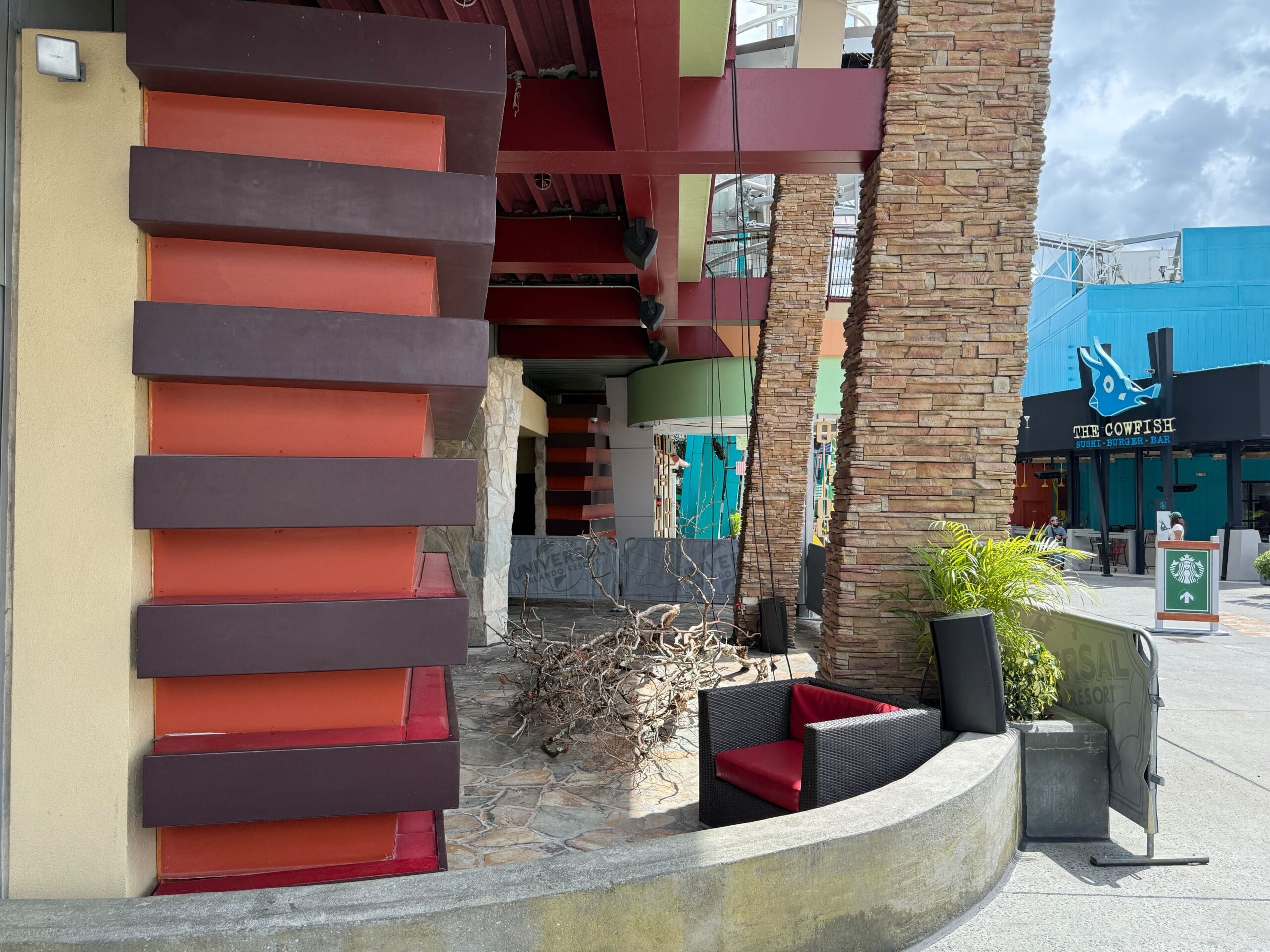 Modern outdoor seating with red chairs, stone walls, and a Firefly Fun House Sign near the restaurant entrance.
