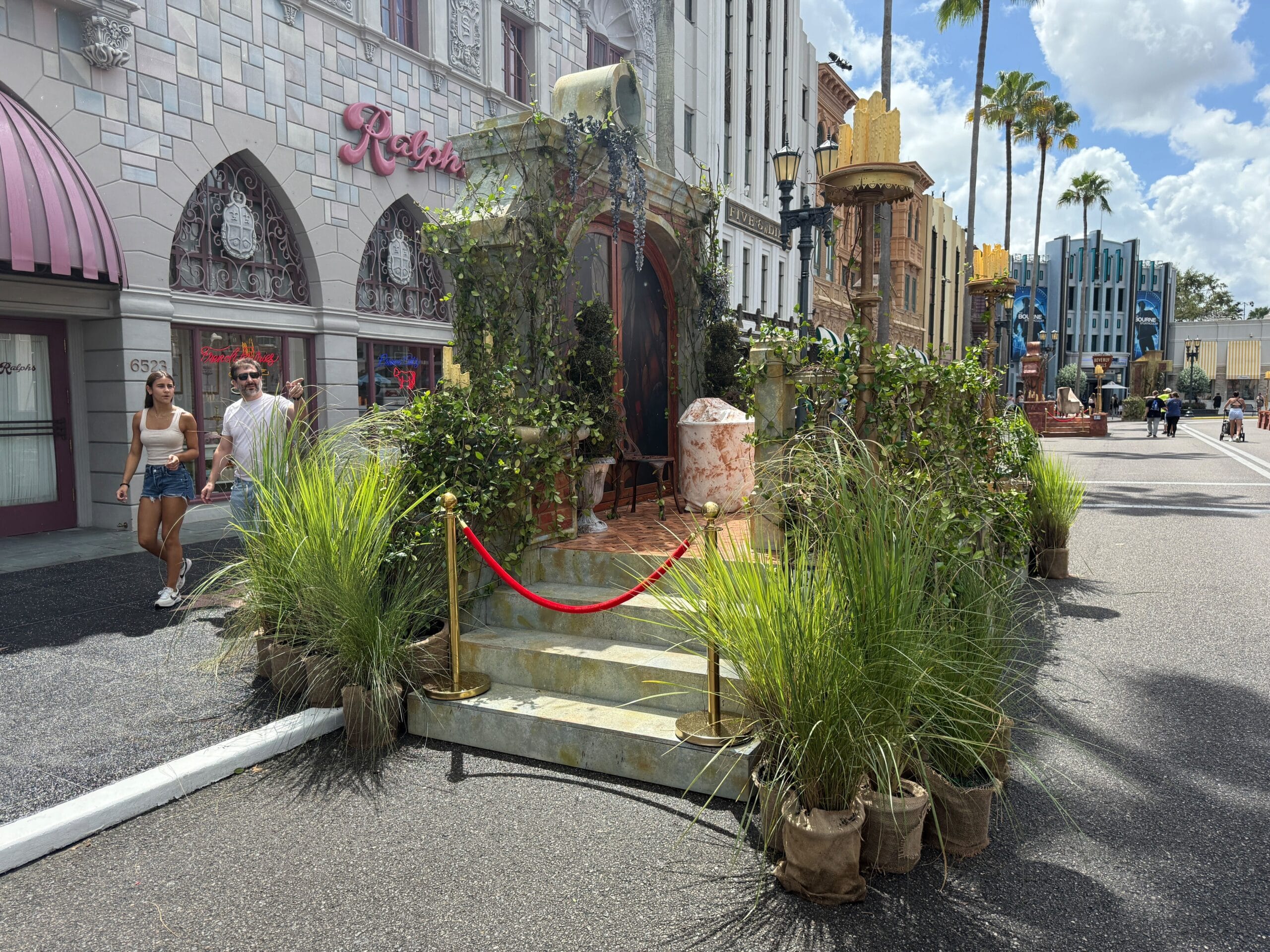 Outdoor movie set with plants, fake stones, and a Firefly Fun House Sign on a city street during Halloween Horror Nights 34.