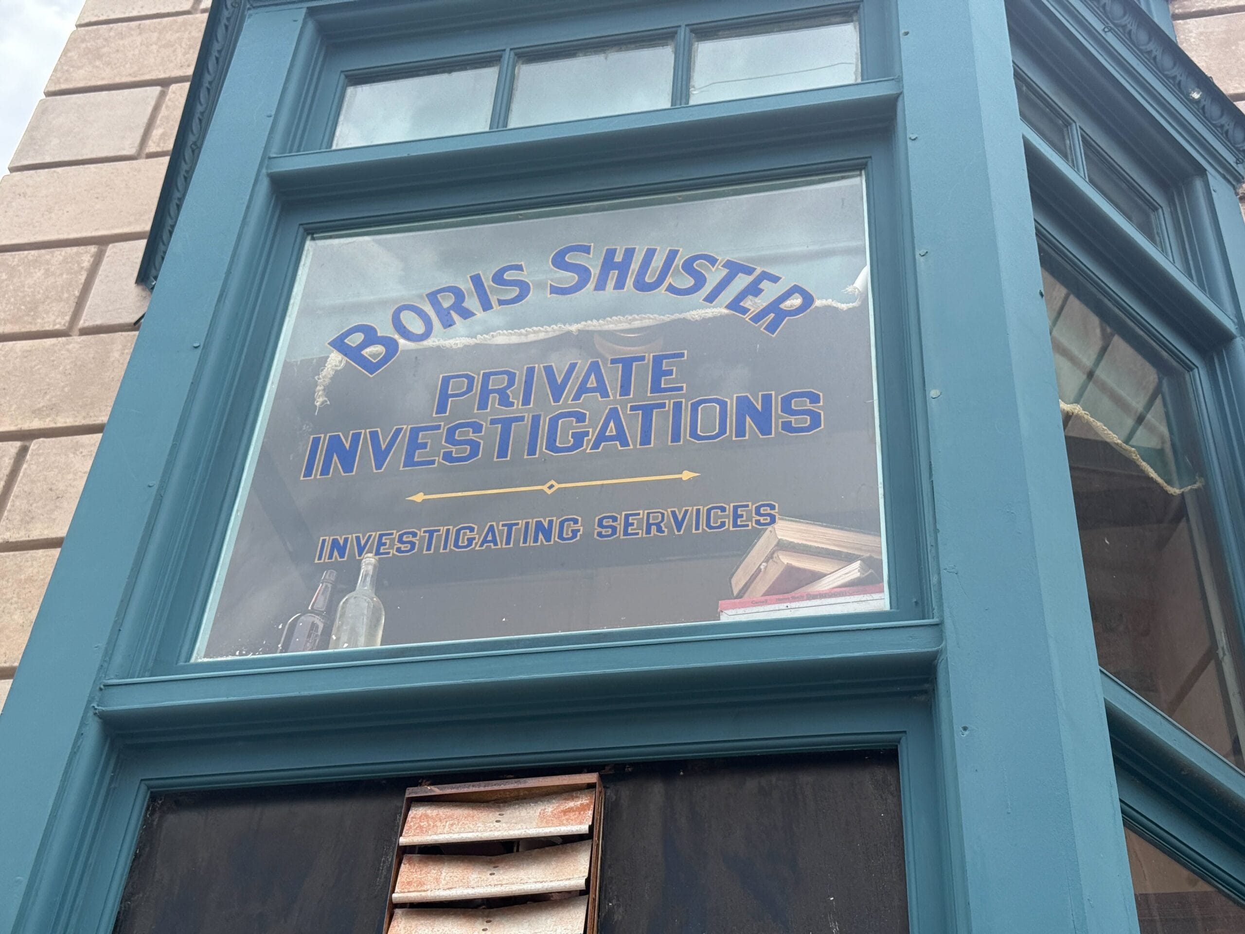 A window sign reads "Boris Shuster Private Investigations Investigating Services" in blue and yellow letters.