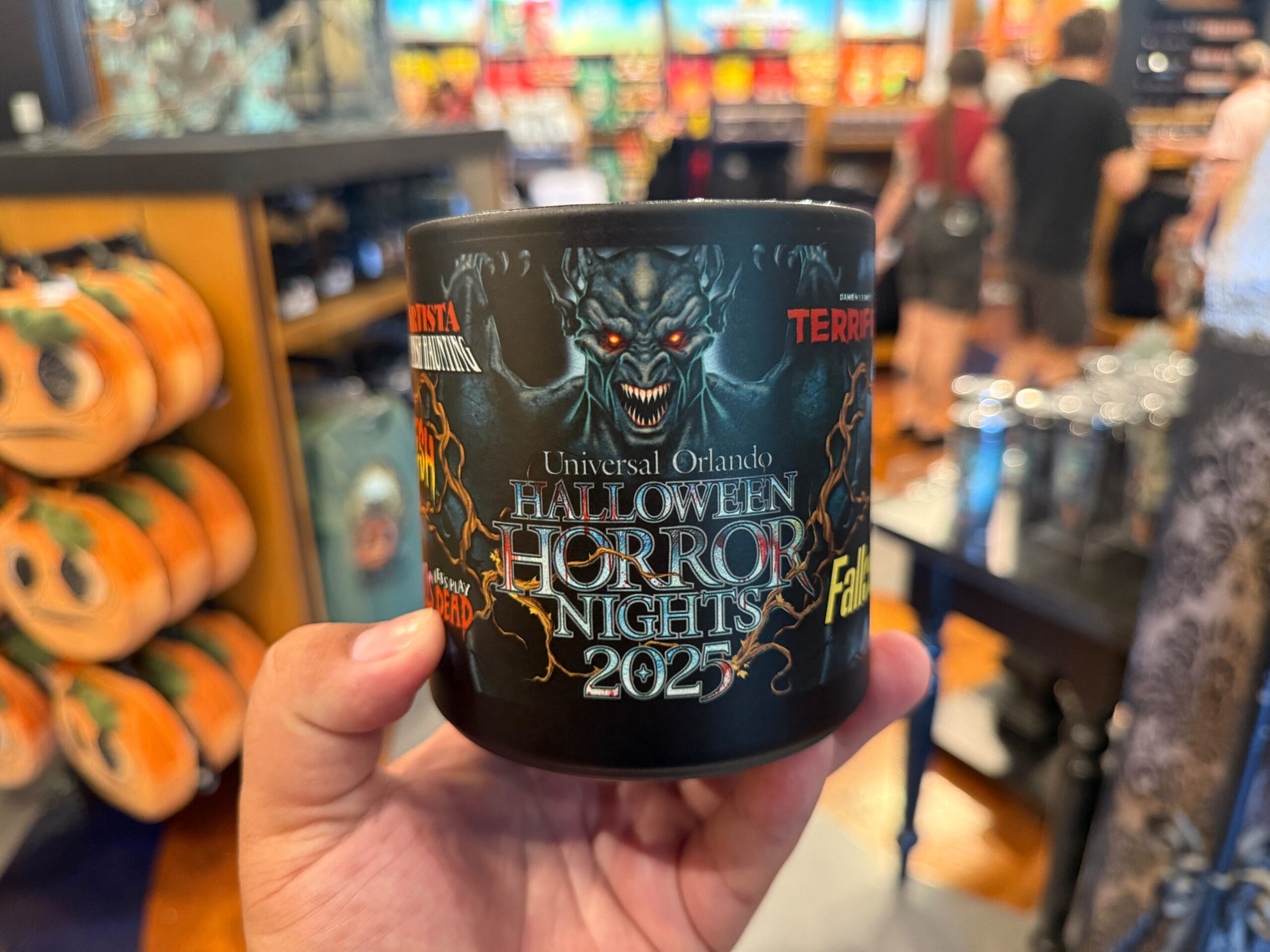 Hand holding a “Halloween Horror Nights 2025” mug, part of exclusive HHN Merch 2025 at Universal Orlando Resort.