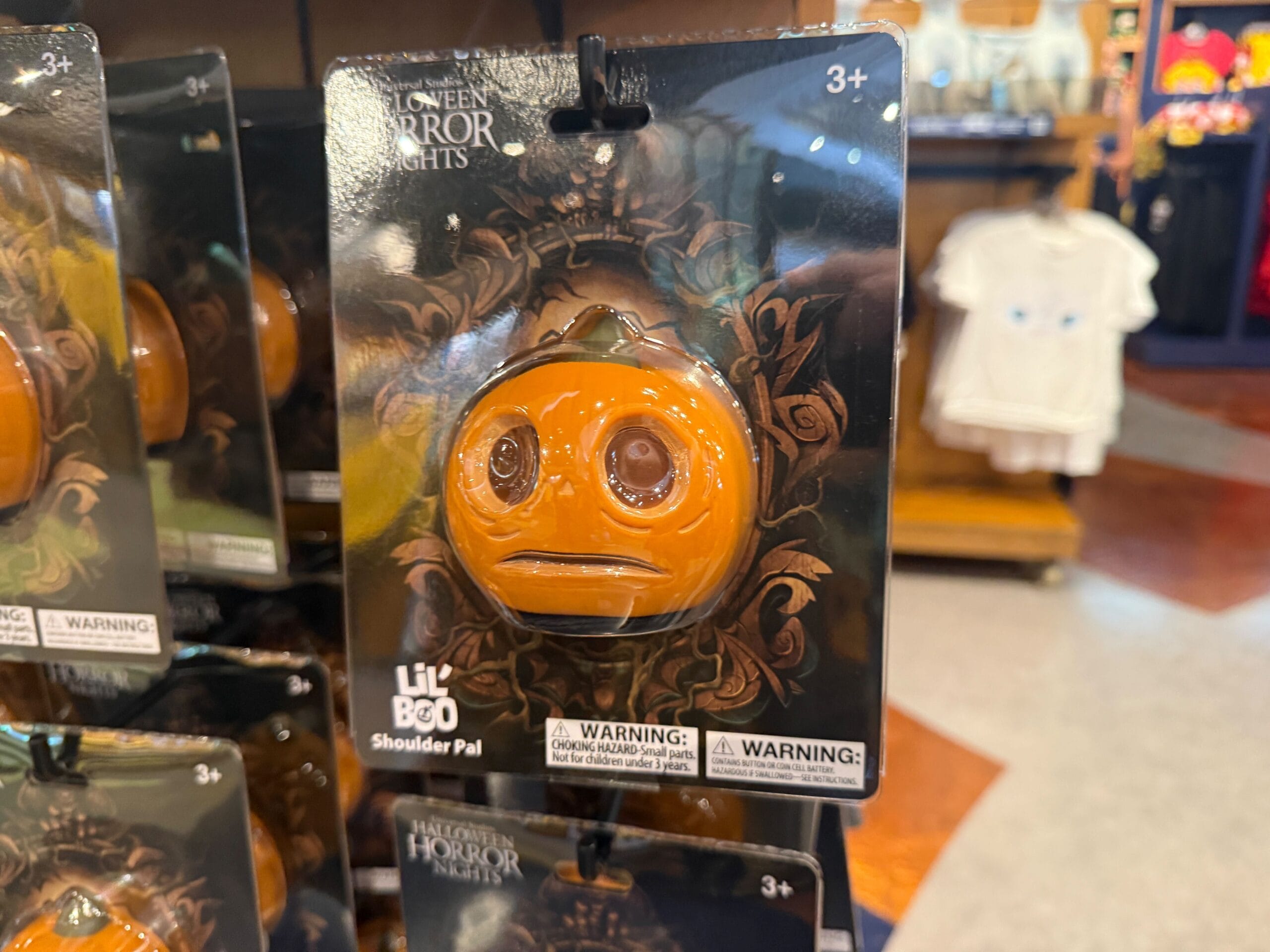 A small orange pumpkin shoulder pal toy with a sad face, part of Universal Orlando Resort Halloween Horror Nights merchandise.