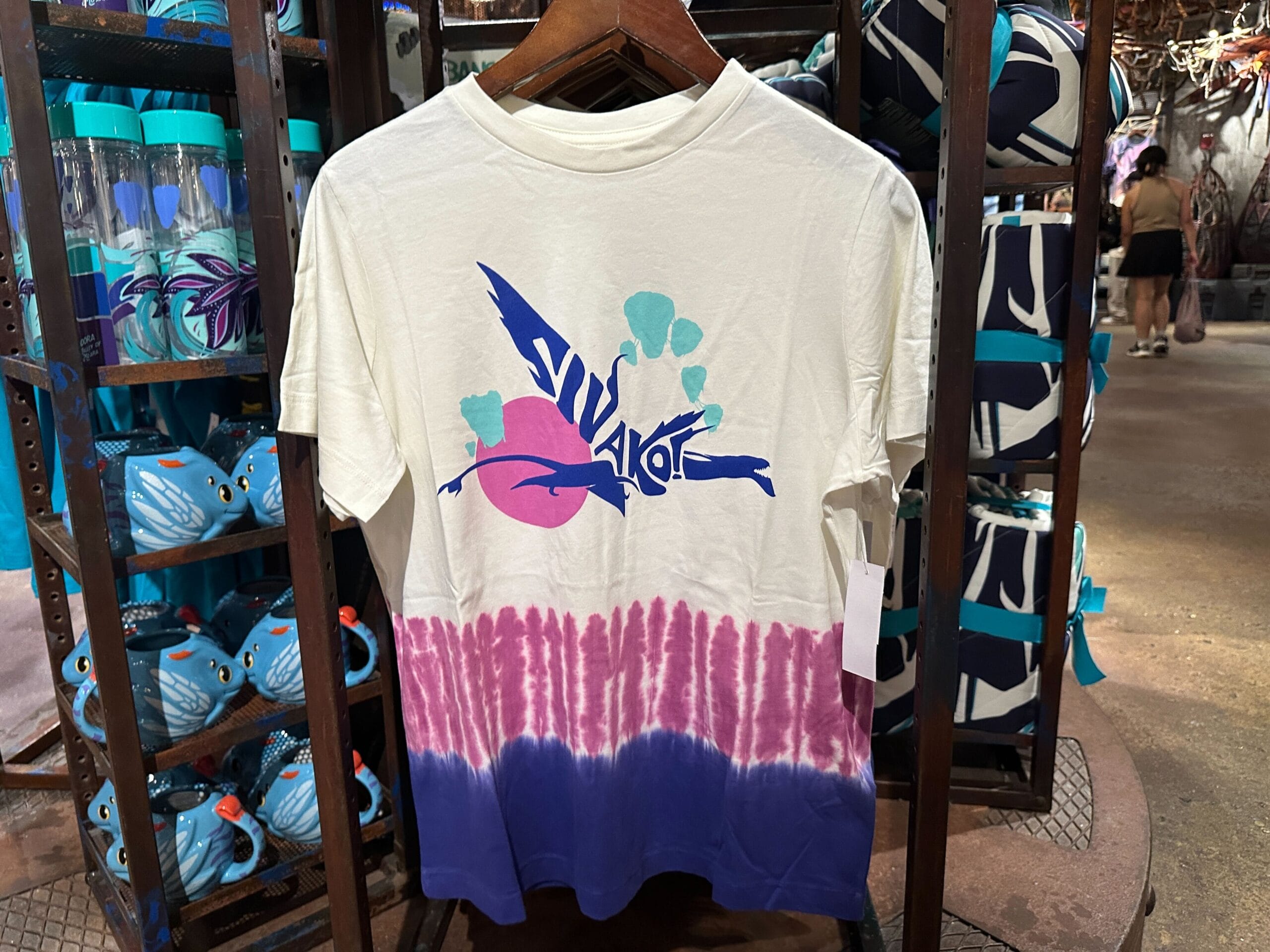 White t-shirt with pink and purple tie-dye, featuring an illustrated banshee—official Pandora Merch, displayed in a store.