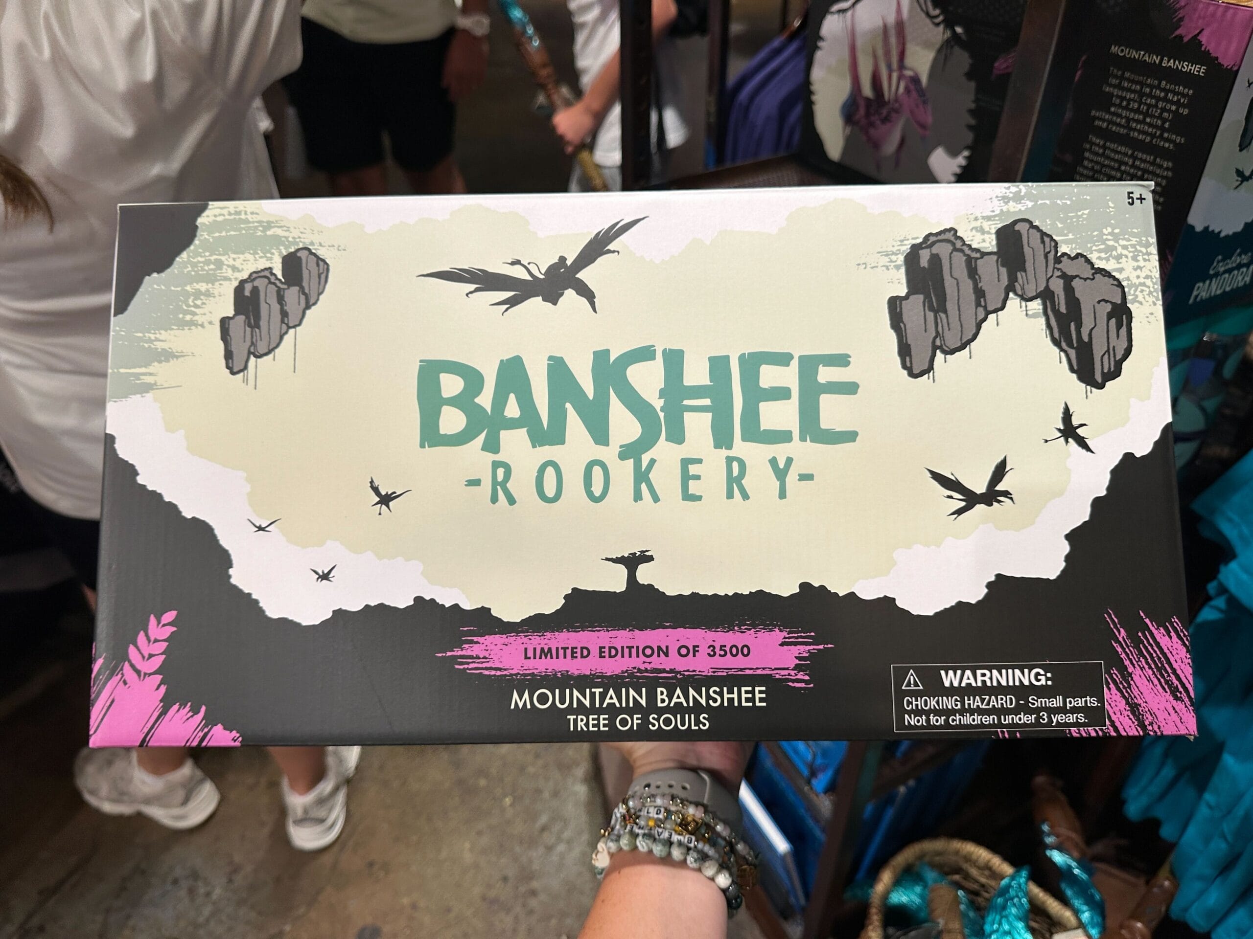 A person holds a limited edition Pandora Merch “Banshee Rookery” toy box with flying banshees and a warning label.