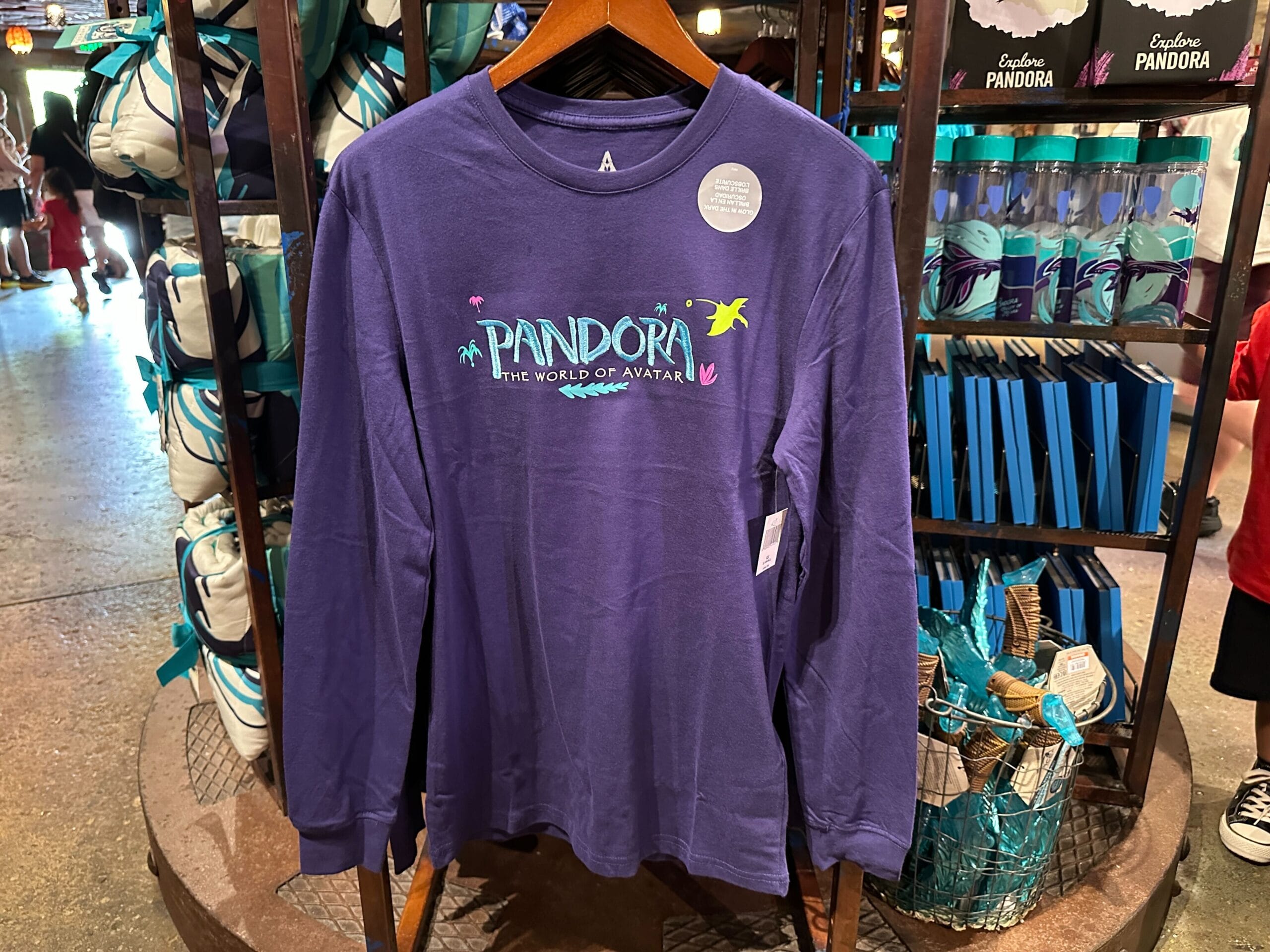 Purple long-sleeve Pandora merchandise shirt featuring "Pandora The World of Avatar" design on a store rack.