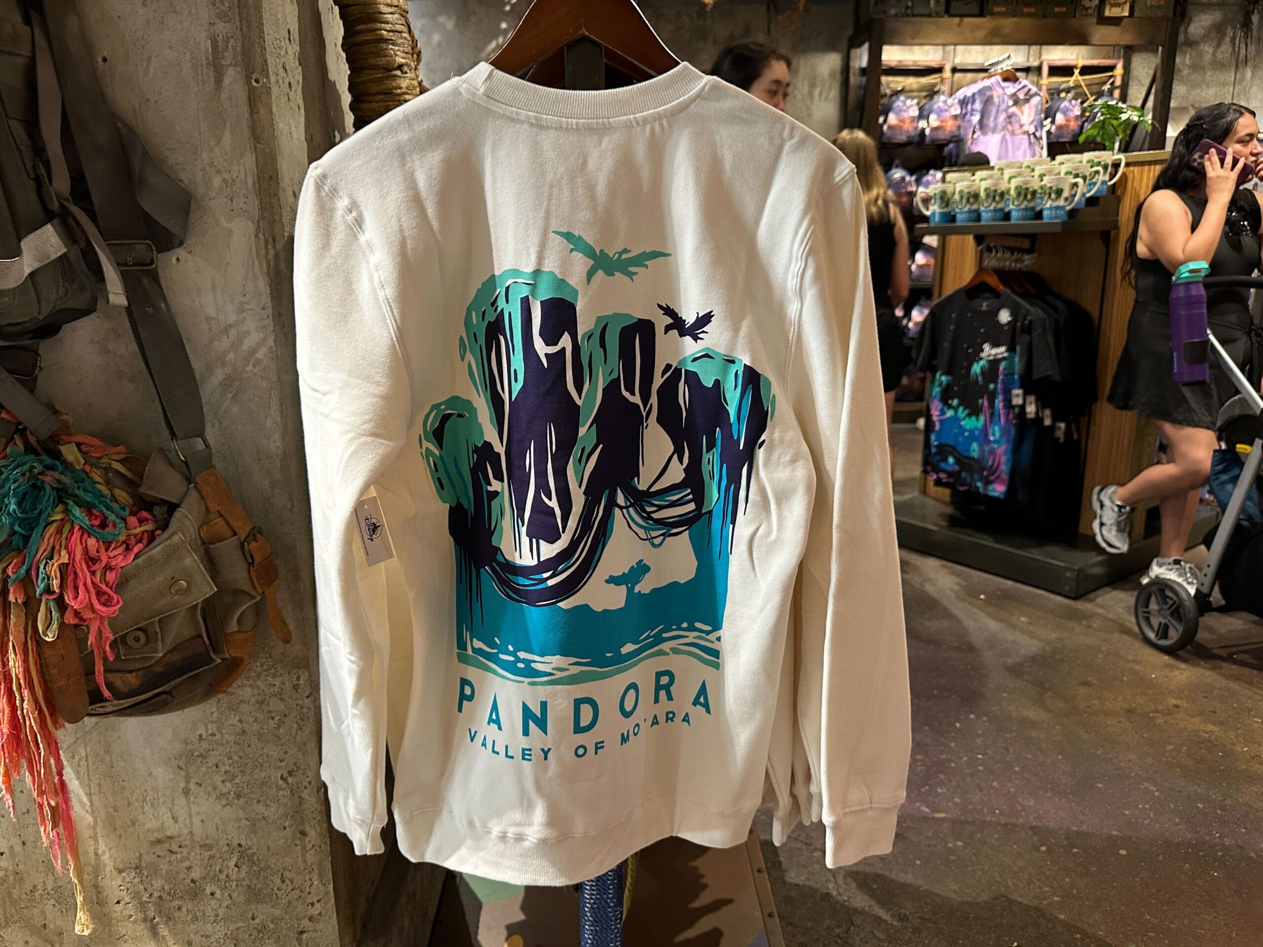 White long-sleeve shirt with "Pandora Valley of Mo'ara" and floating mountains graphic, perfect Pandora Merch find in-store.