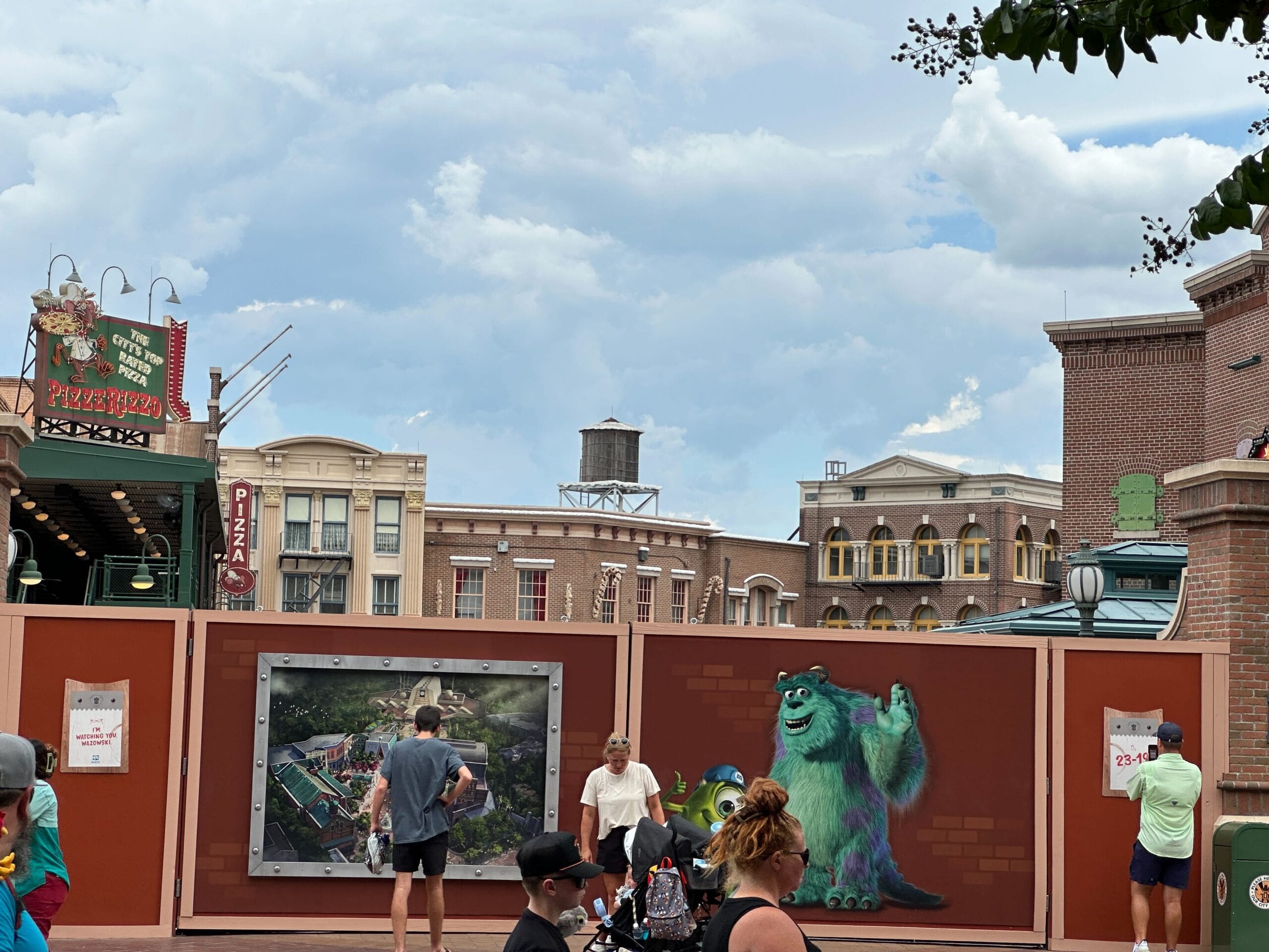 People walk by construction walls with a Sulley mural near the Muppets Store at Disney's Hollywood Studios plaza.