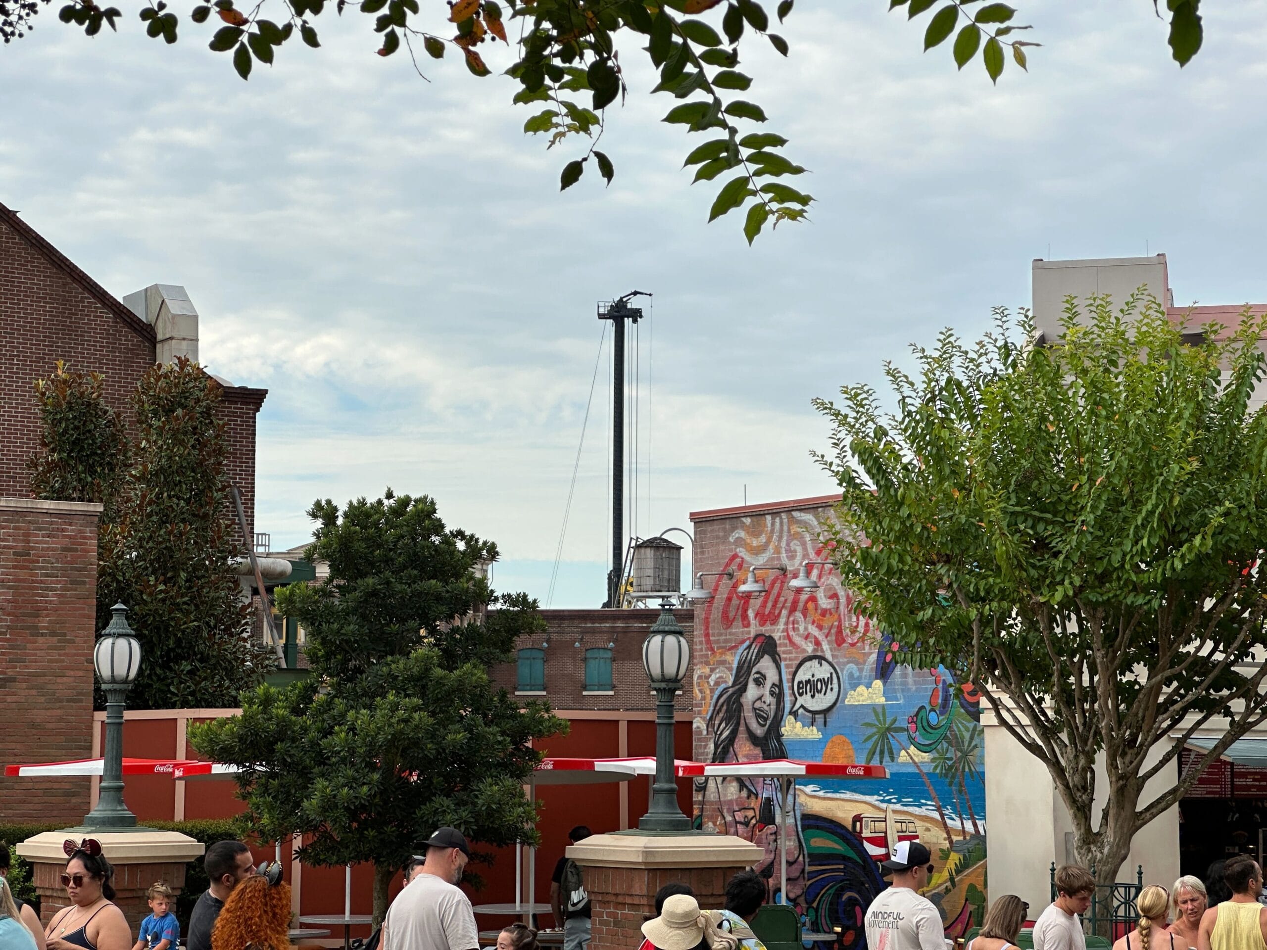 People gather in an outdoor plaza near a mural, with Monster's Inc. Land construction visible at Disney's Hollywood Studios.