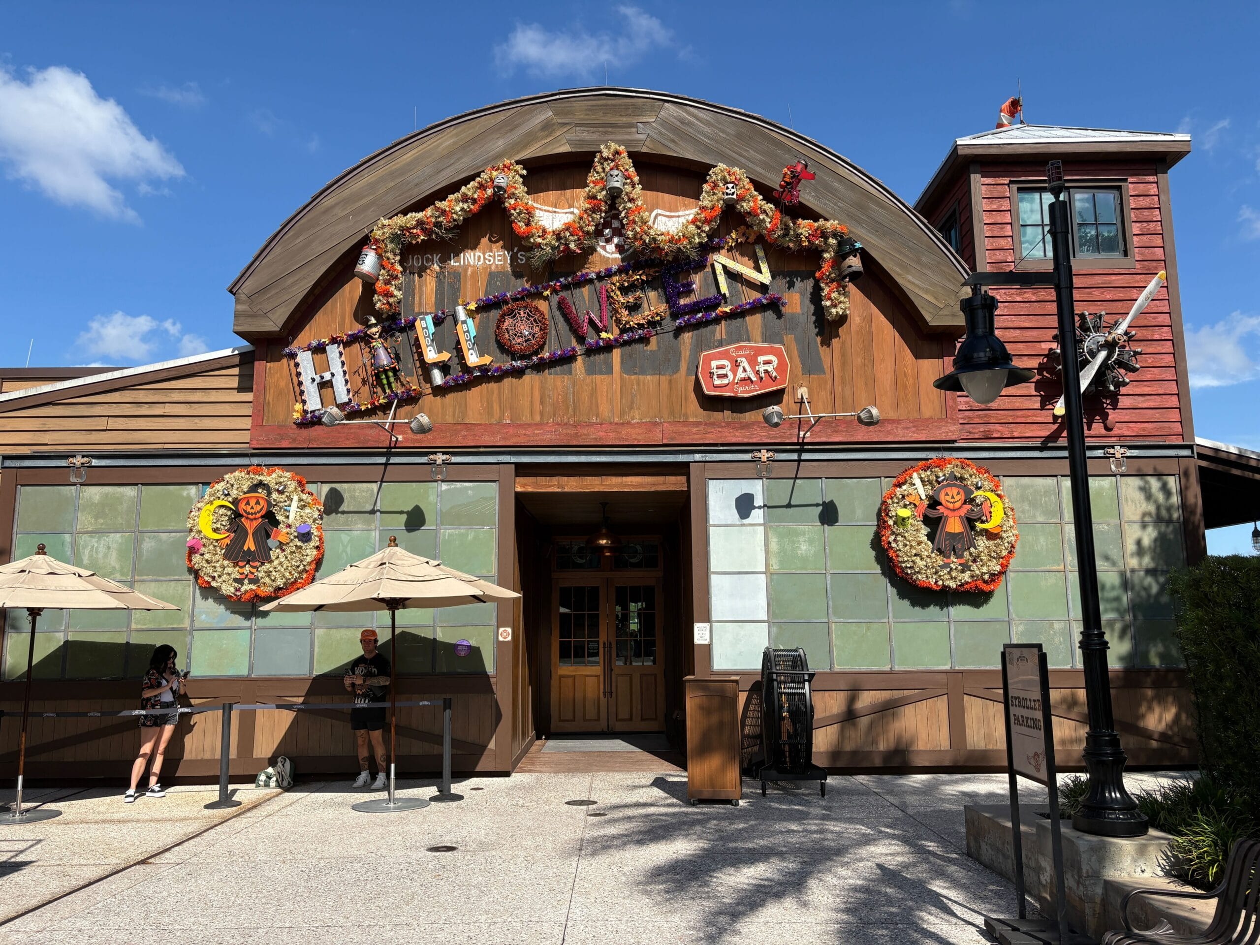 Jock Lindsey's Hangar Bar decorated for Halloween with garlands and gingerbread, under a blue sky at Disney Springs.