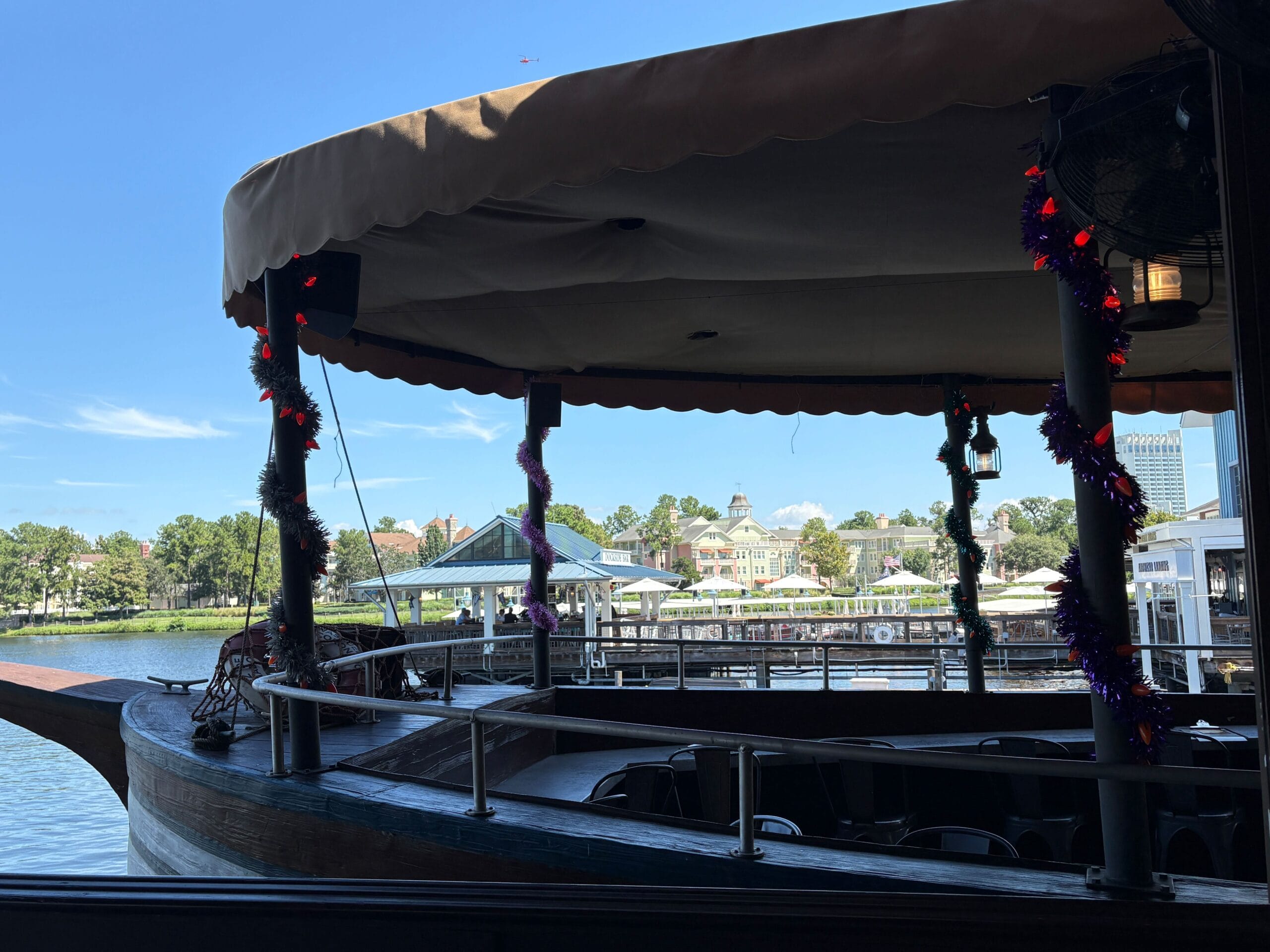 A shaded boat dock at Disney Springs, decorated with a Halloween overlay, overlooks water and Jock Lindsey's Hangar Bar.