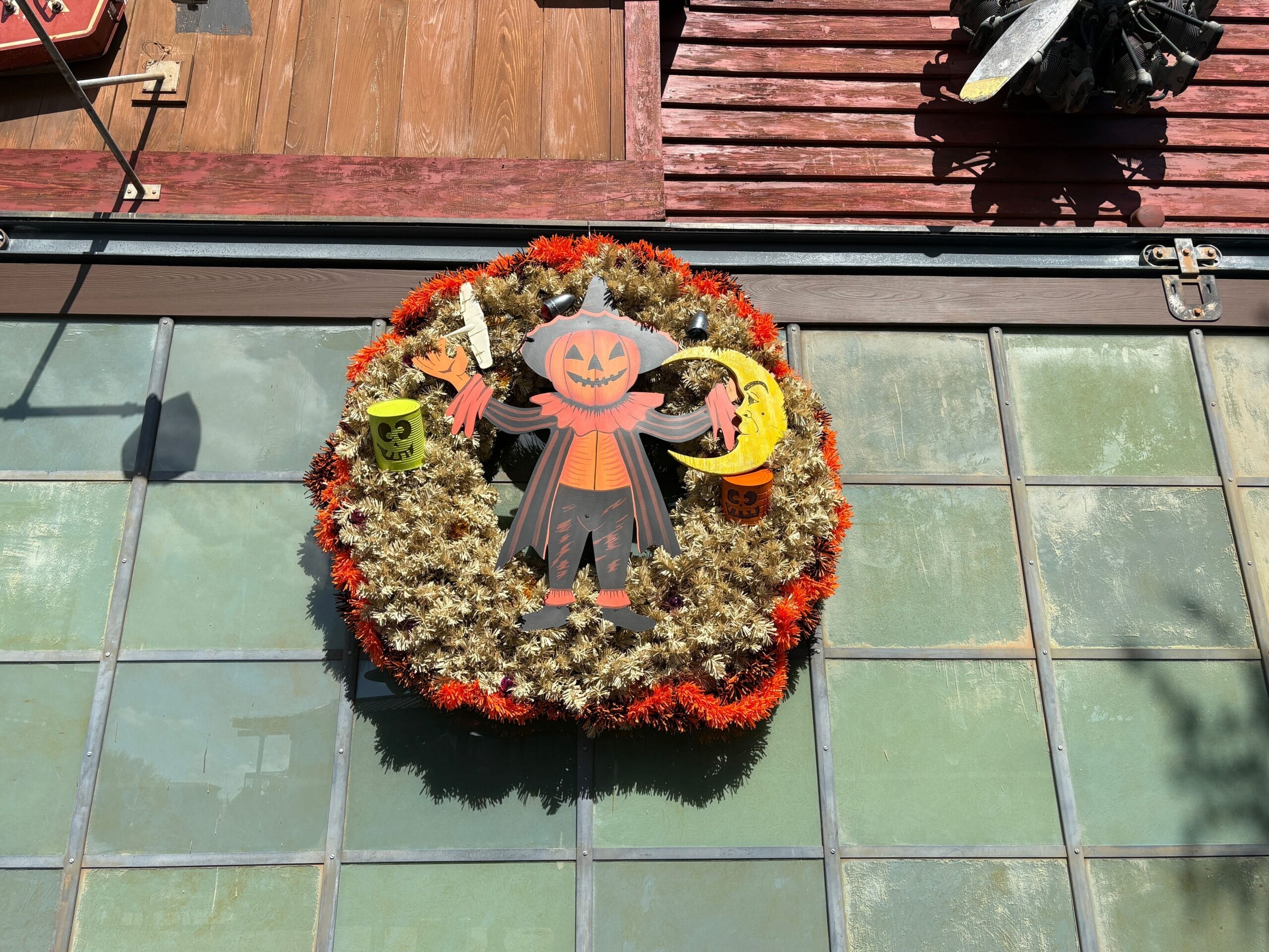 A Halloween wreath with a pumpkin-headed figure decorates a window at Disney Springs in the Halloween Overlay sunlight.
