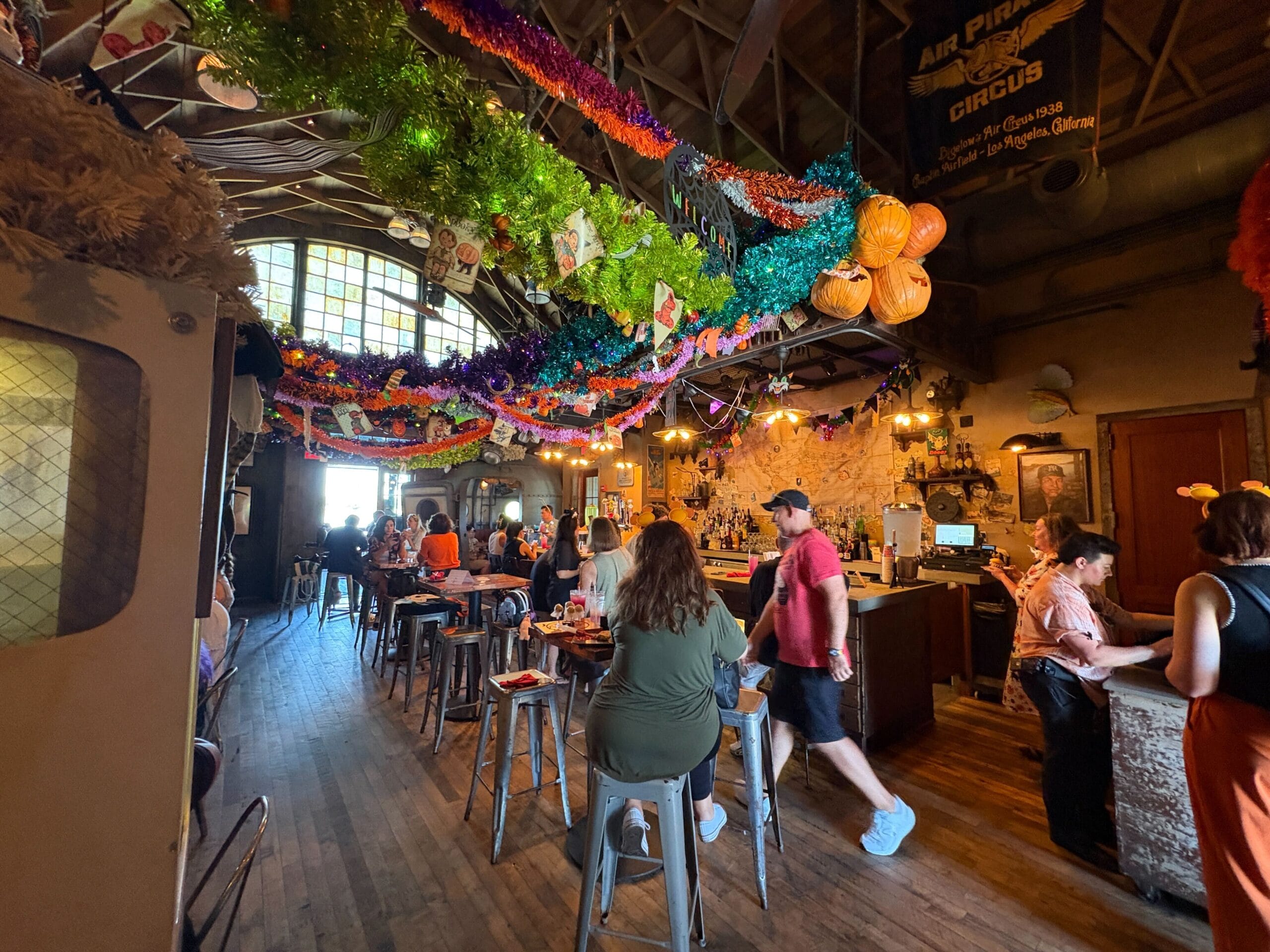 People gather at Disney Springs’ Jock Lindsey's Hangar Bar, enjoying its festive Halloween overlay and pumpkin decor.